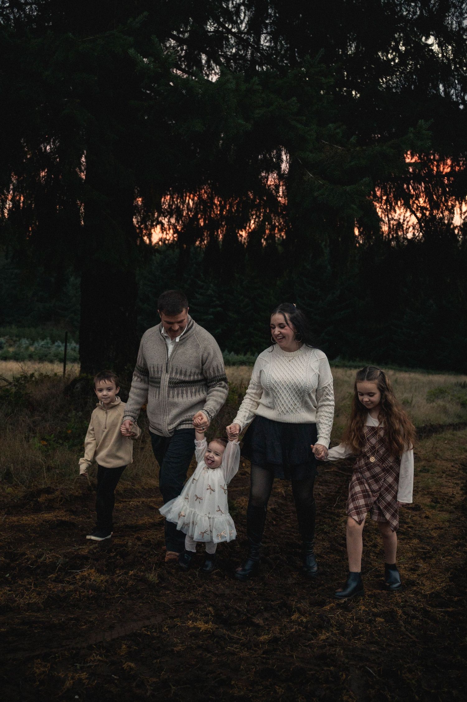 Family of five walking hand-in-hand through a Christmas tree field in the Silverton hills.