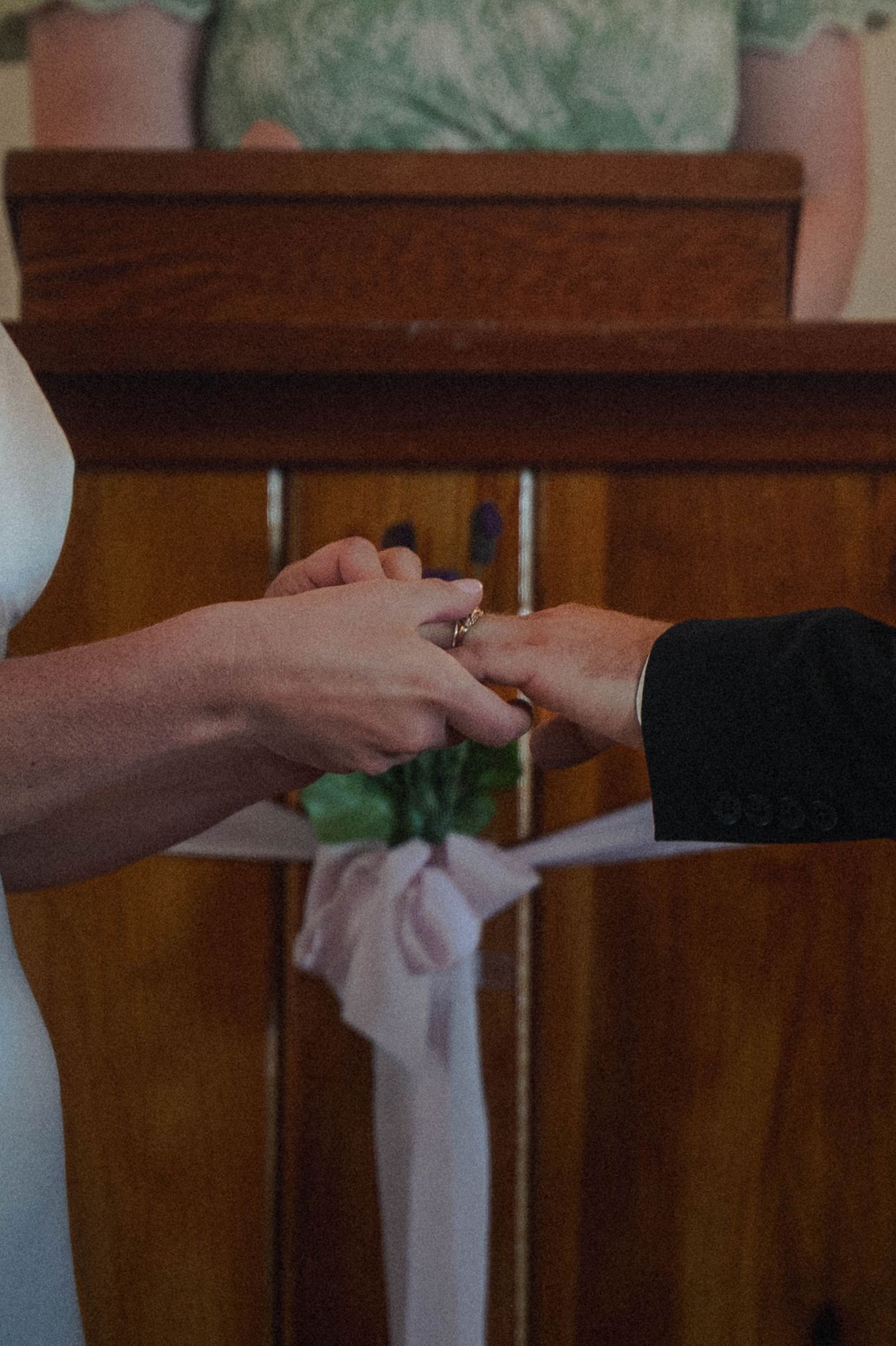 Couple exchanging wedding rings at altar during ceremony, close-up of hands with ring placement.