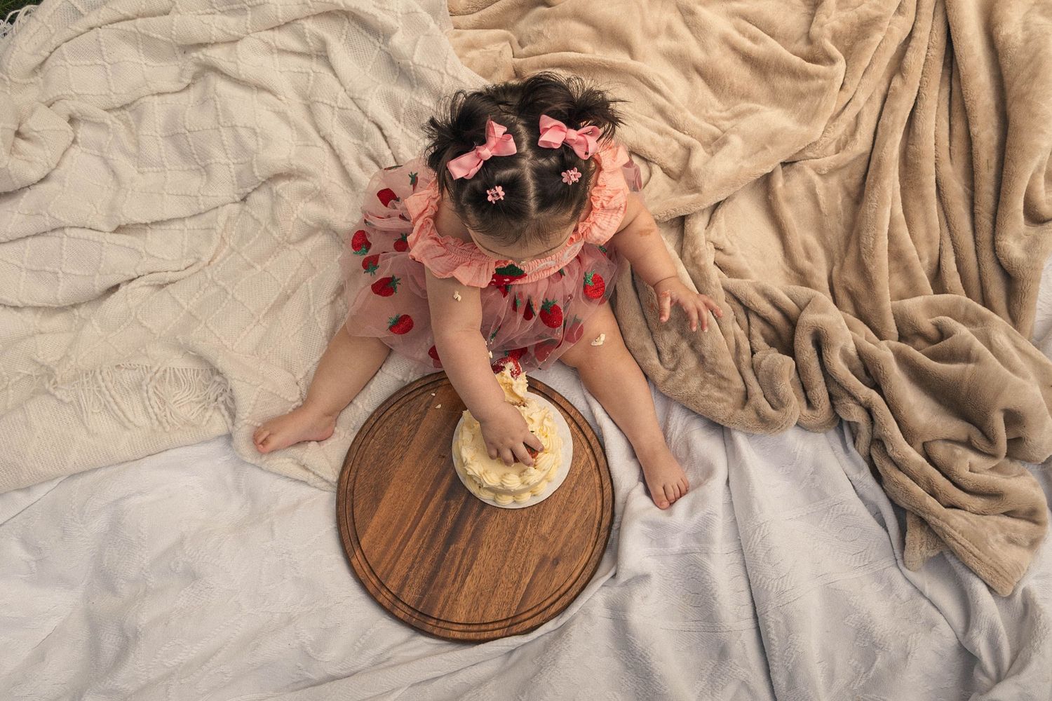Overhead view of cream colored cake with raspberries on rustic wooden serving board.