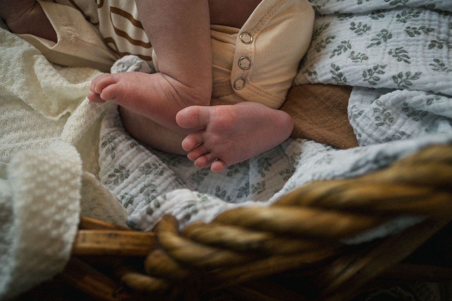 Close-up detail of tiny baby feet against soft white blankets.