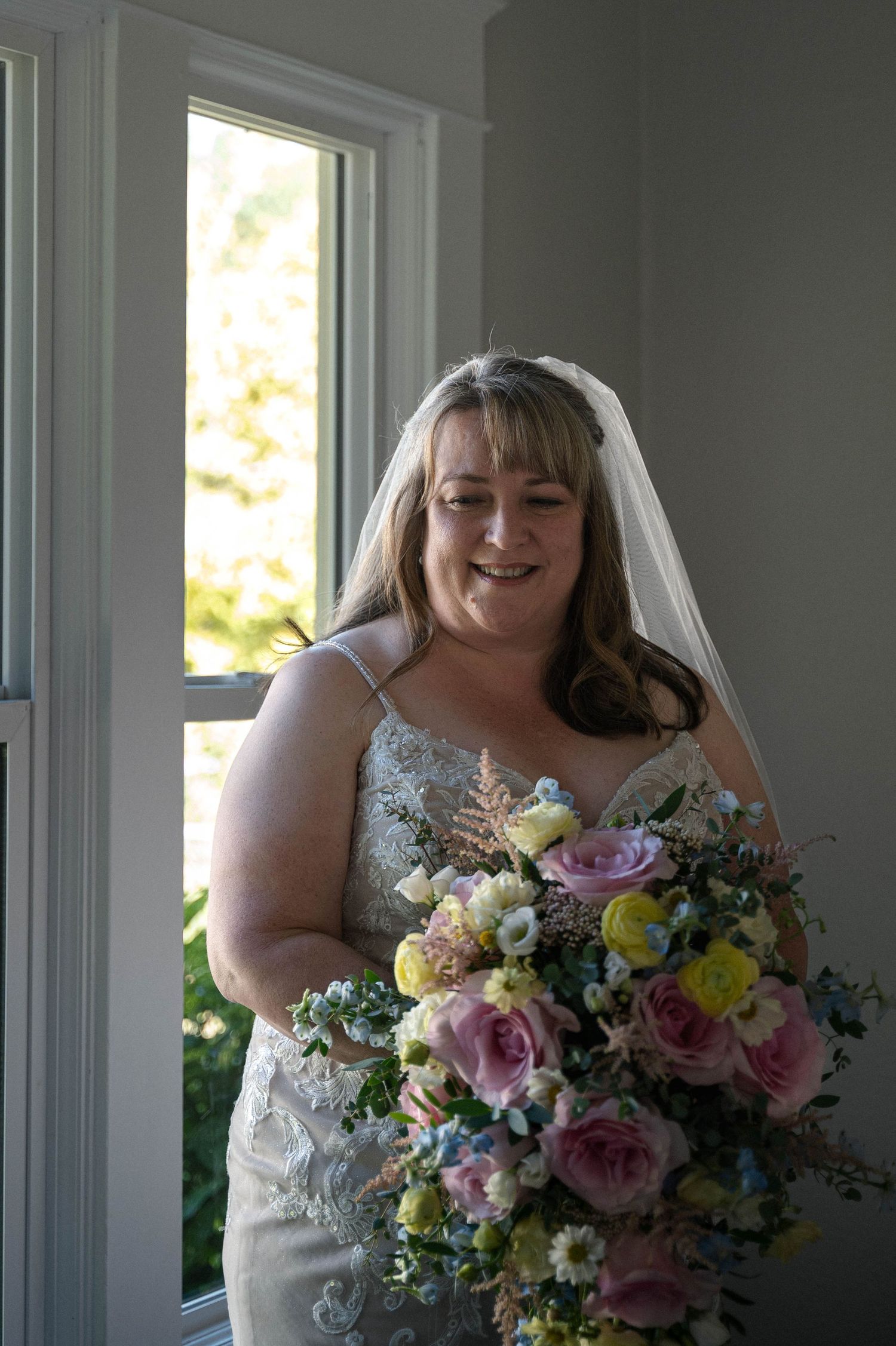 Bridal bouquet featuring pink and purple roses with mixed seasonal flowers.