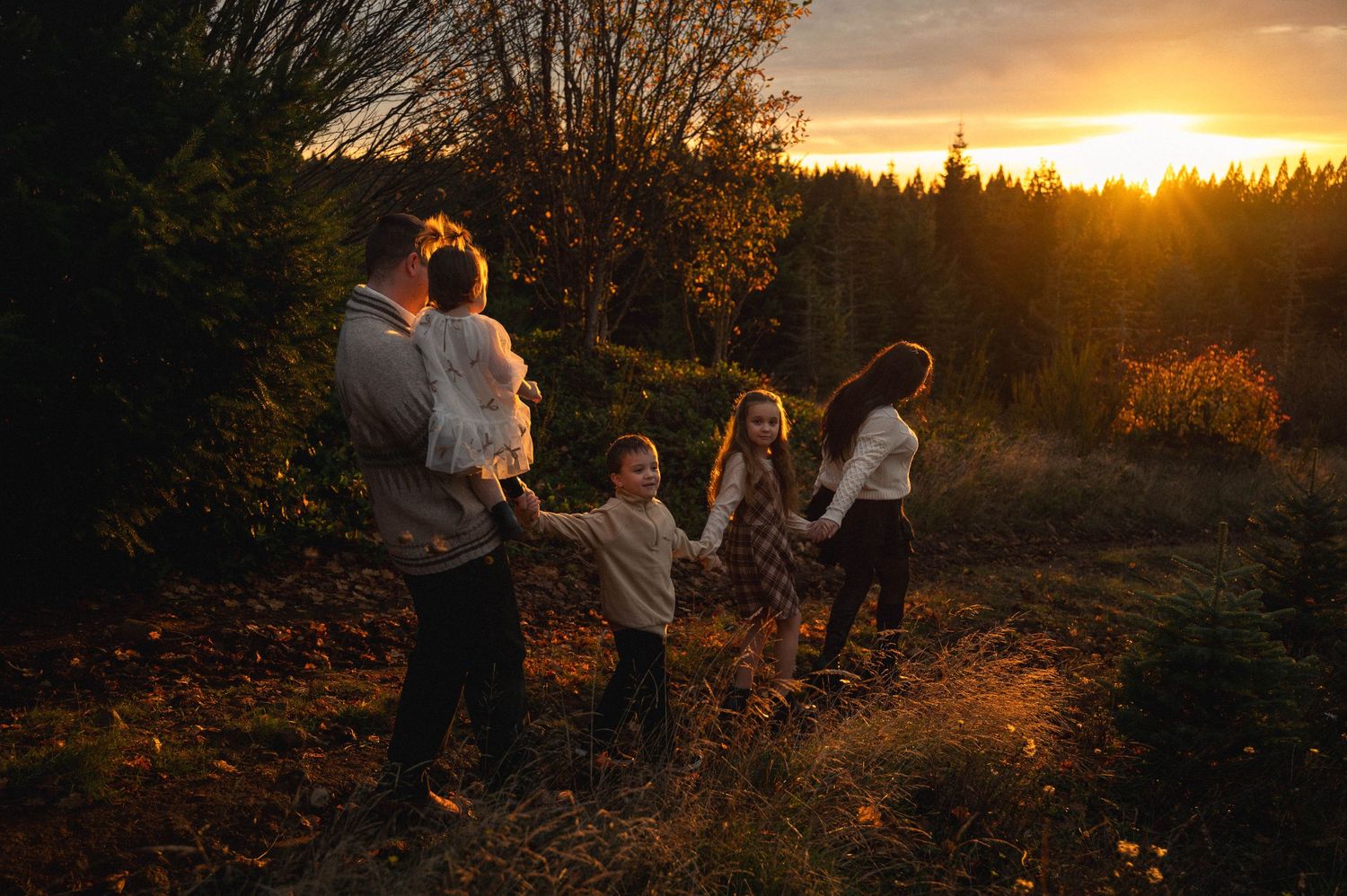 Moody landscape of family of 5, walking hand in hand all in a row, down the trails of Steffen's Conifer Farm in Silverton, Oregon