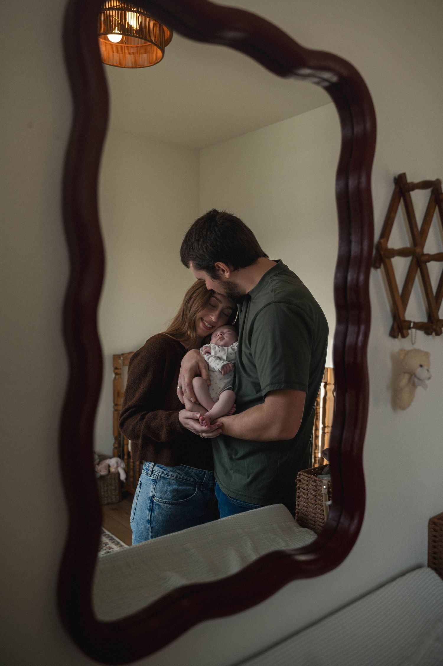 A series of mirror reflections showing a couple in a tender embrace against a white wall with dark wooden framed mirrors.