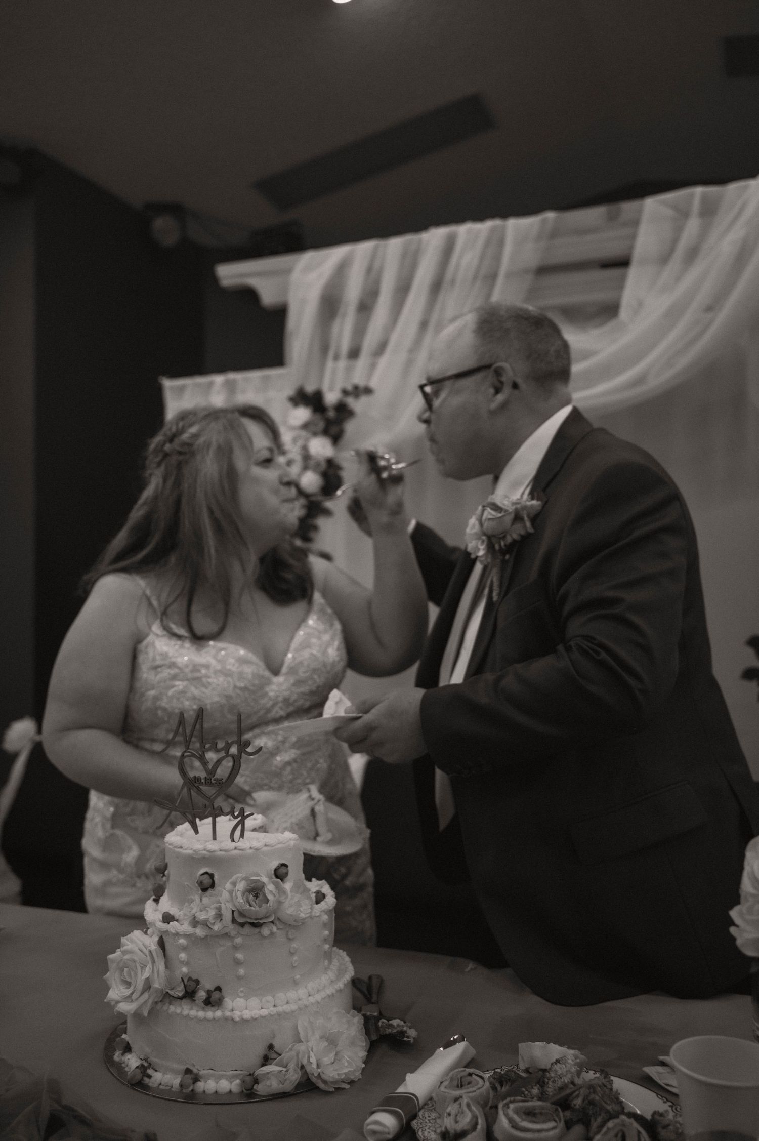 Wedding couple sharing cake cutting moment at reception table.
