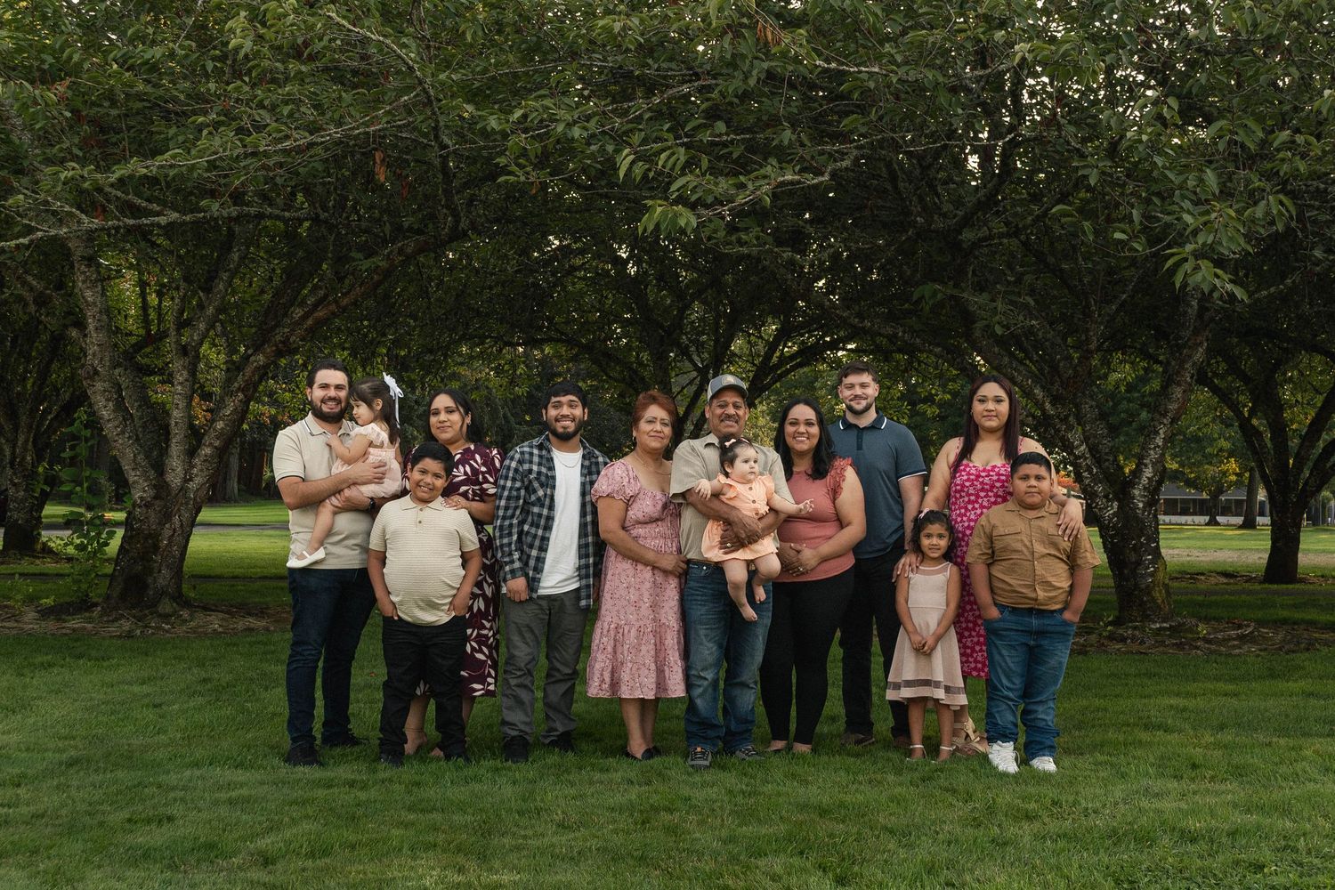 Extended family, grandparents, parents, and grandchildren, all posed in a line at a park in Stayton, Oregon.