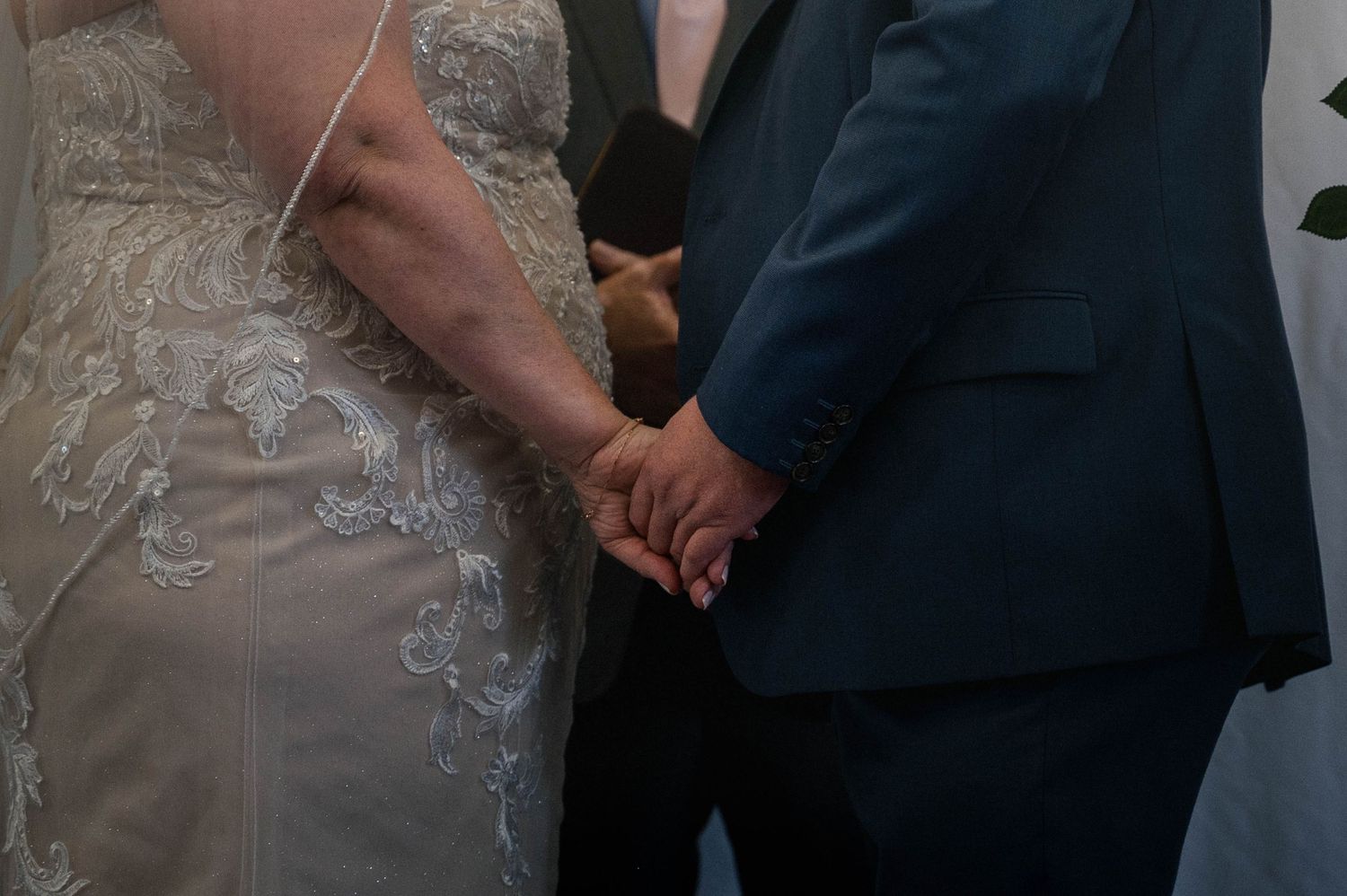 Close-up of wedding ceremony details showing formal attire and joined hands.
