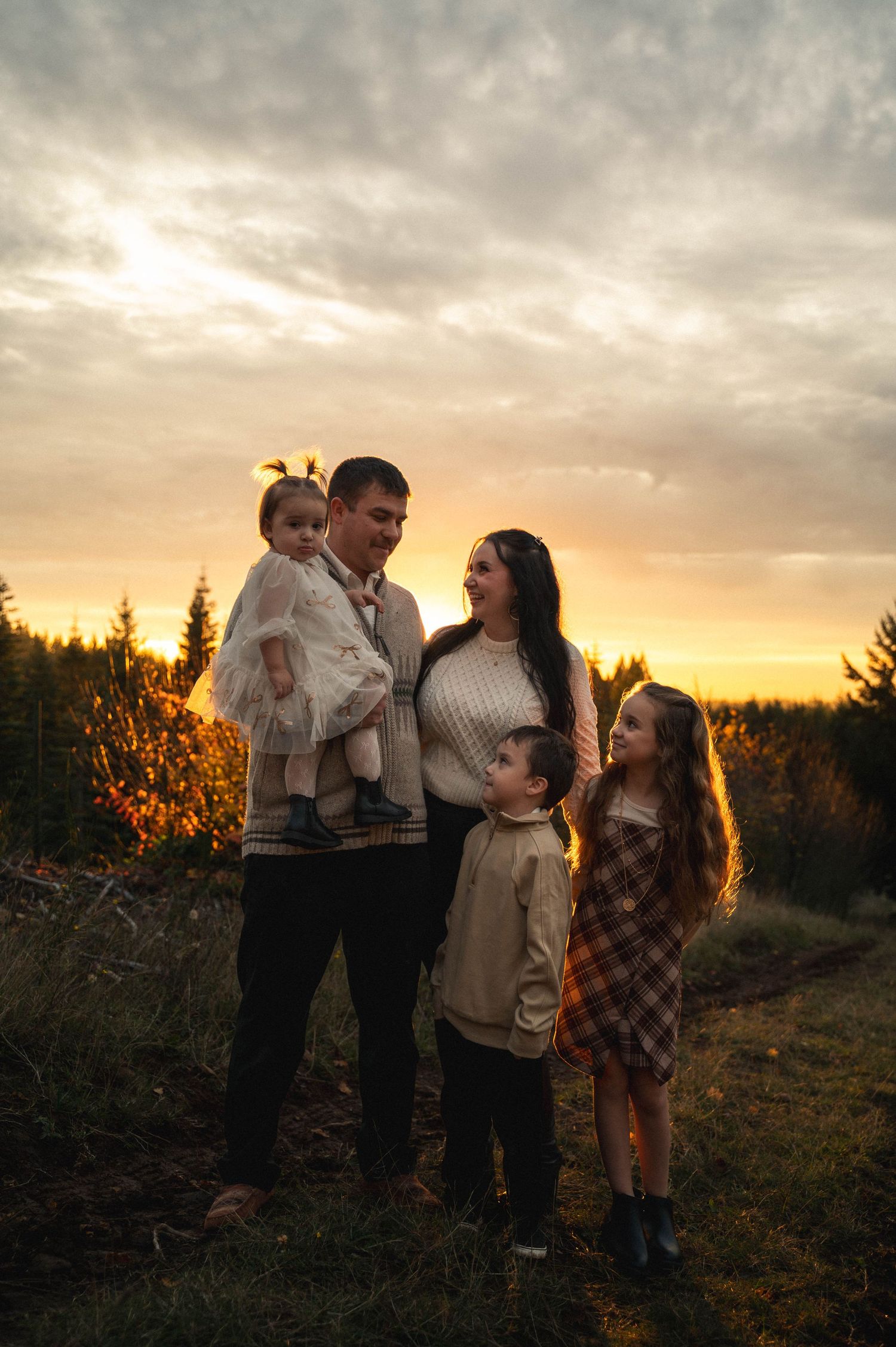 Family of 5 standing close together, posing at sunset at a local Christmas tree farm in Silverton, Oregon.