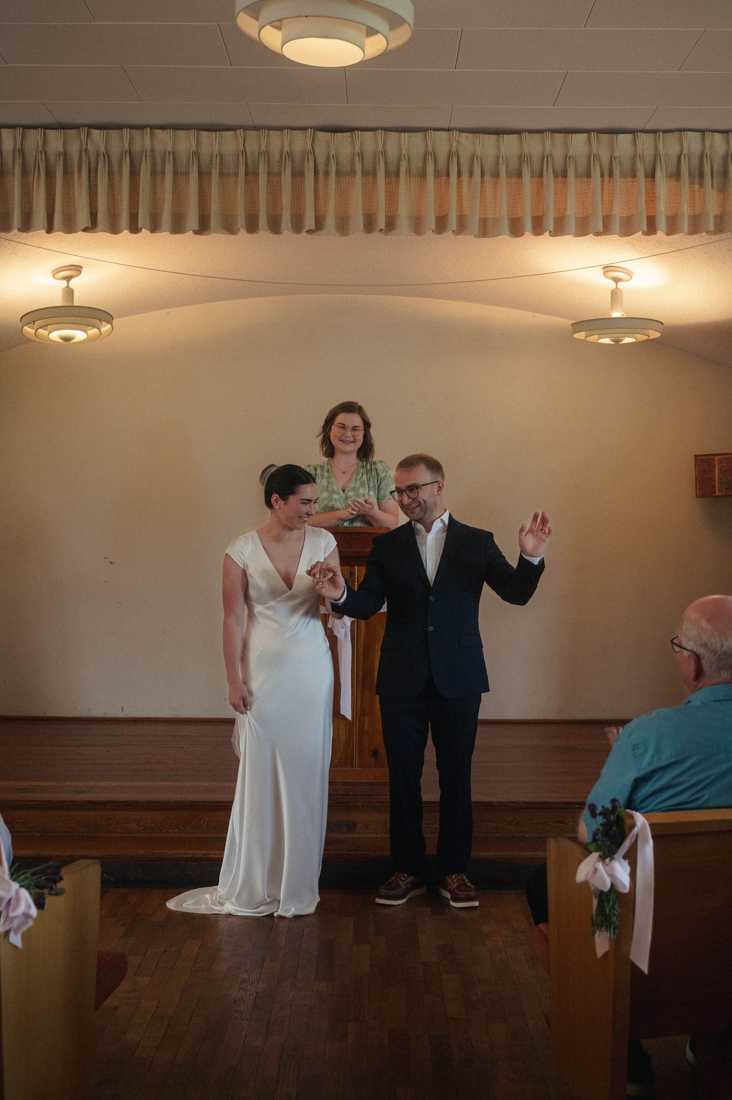 Bride and groom celebrate at wedding altar with officiant in small chapel.