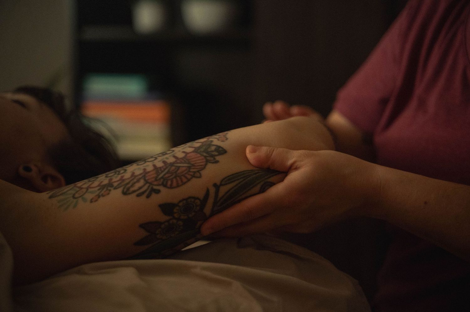Close-up view of a detailed floral tattoo on an arm in dim lighting.