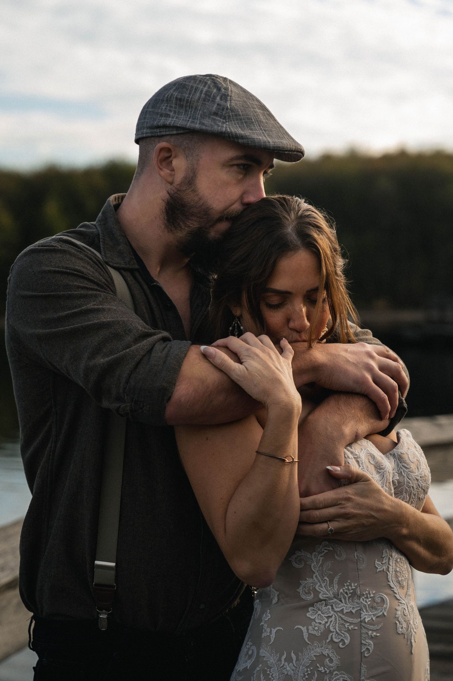A couple in wedding attire embraces tenderly by a lake during sunset in a romantic photo sequence.