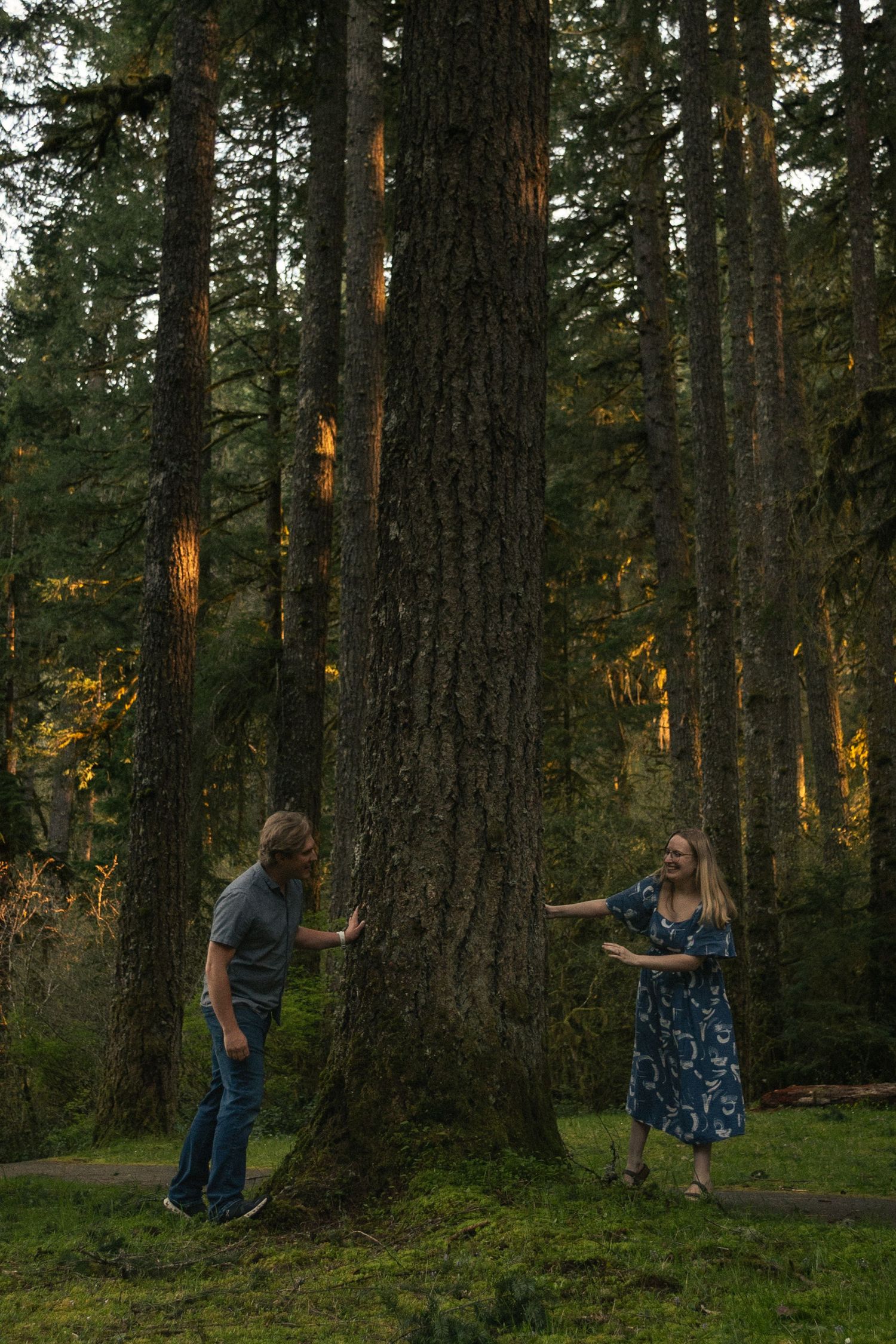 couple peeking around a tree at eachother at Silver Falls State Park by Moon Street Photography