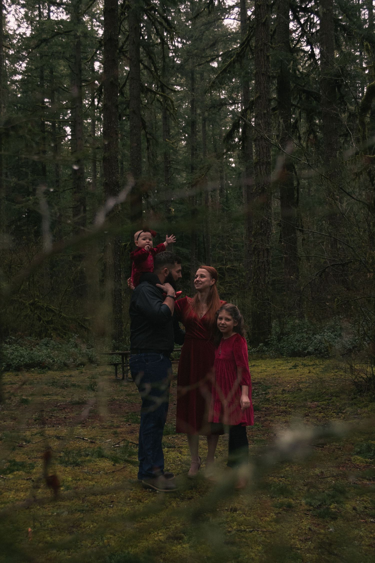 A family dressed in red enjoys quality time together in a misty forest clearing.