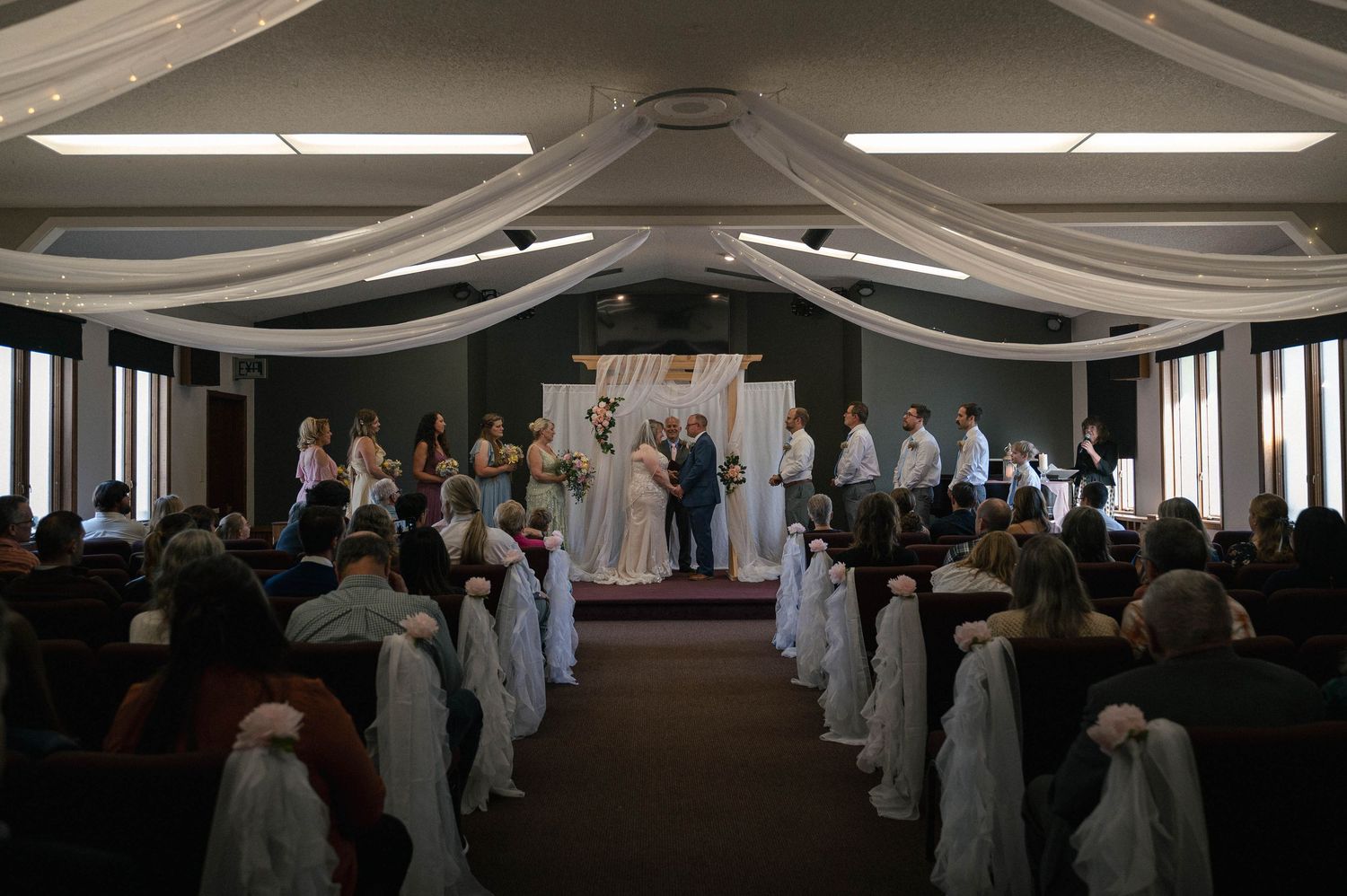 Wedding reception venue decorated with elegant white draping and floral arrangements.