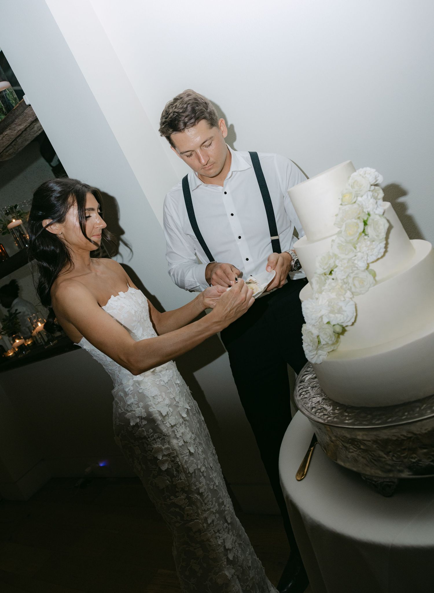 Wedding cake cutting moment with a white tiered cake decorated with flowers.