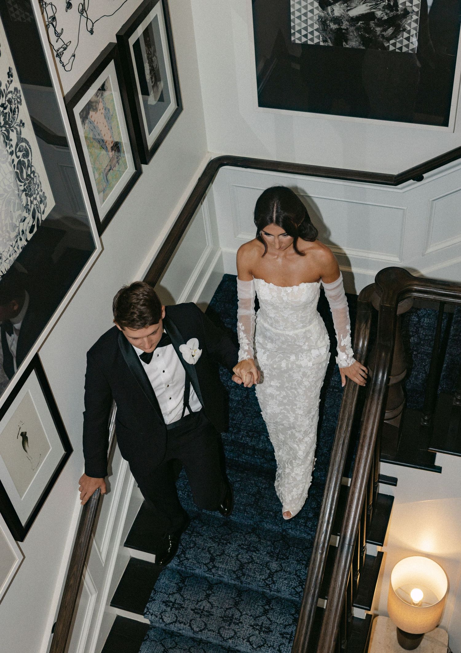 A couple navigates down ornate stairs during their wedding celebration.