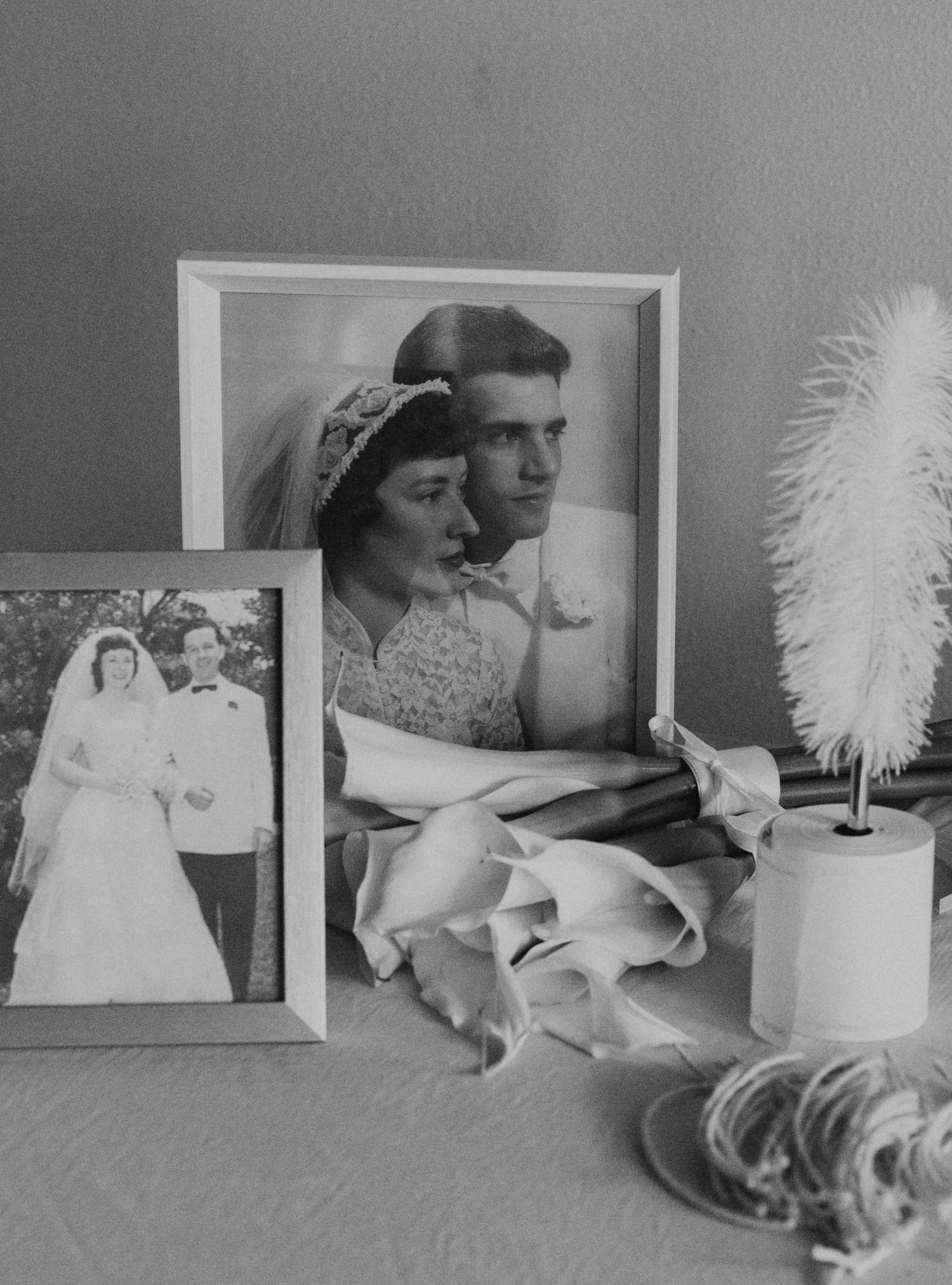 Black and white vintage photographs displayed alongside white florals and feather accents.