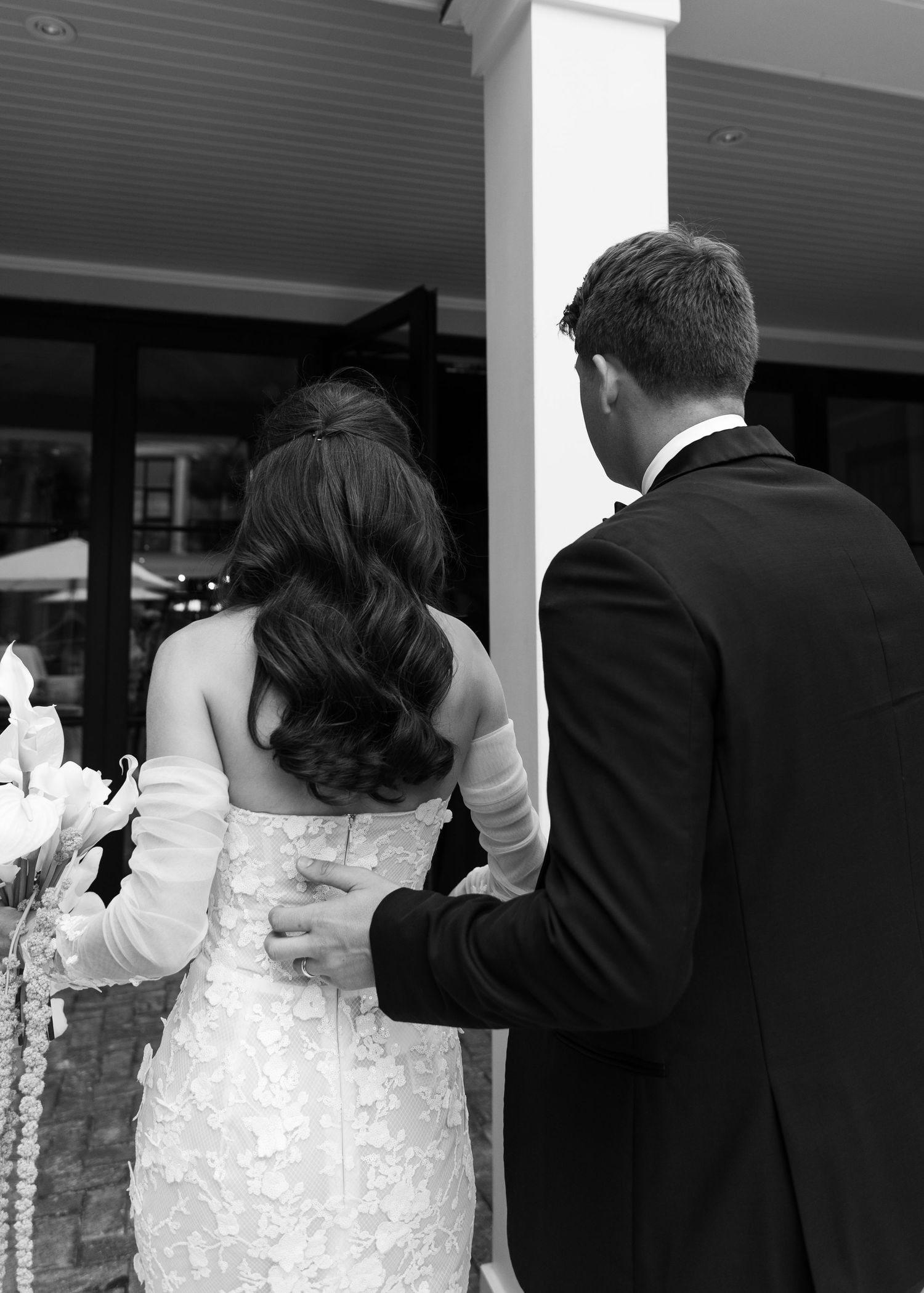 Black and white formal attire seen from behind at an elegant wedding reception.