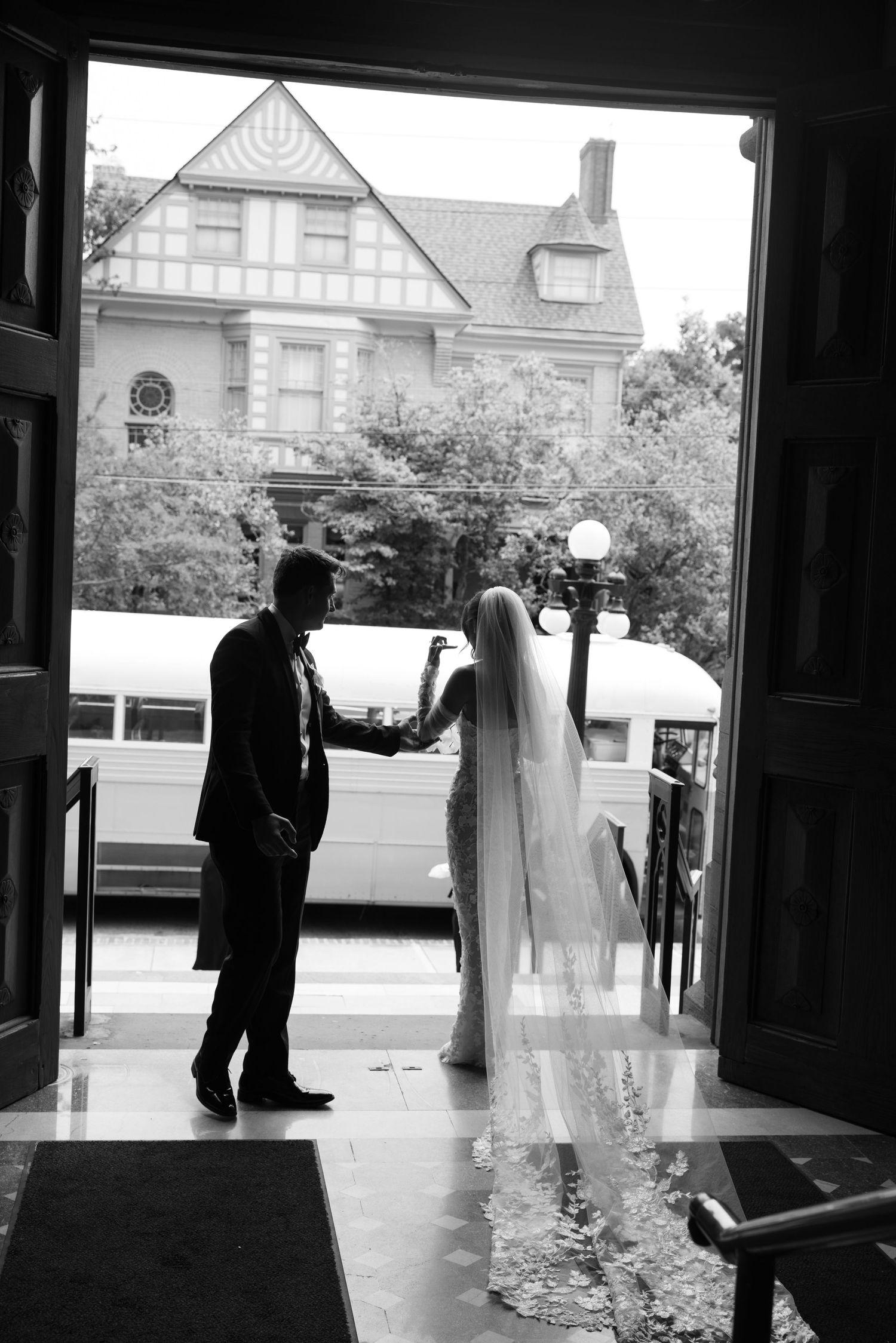 Wedding party silhouettes framed in church doorways with buildings visible in background.