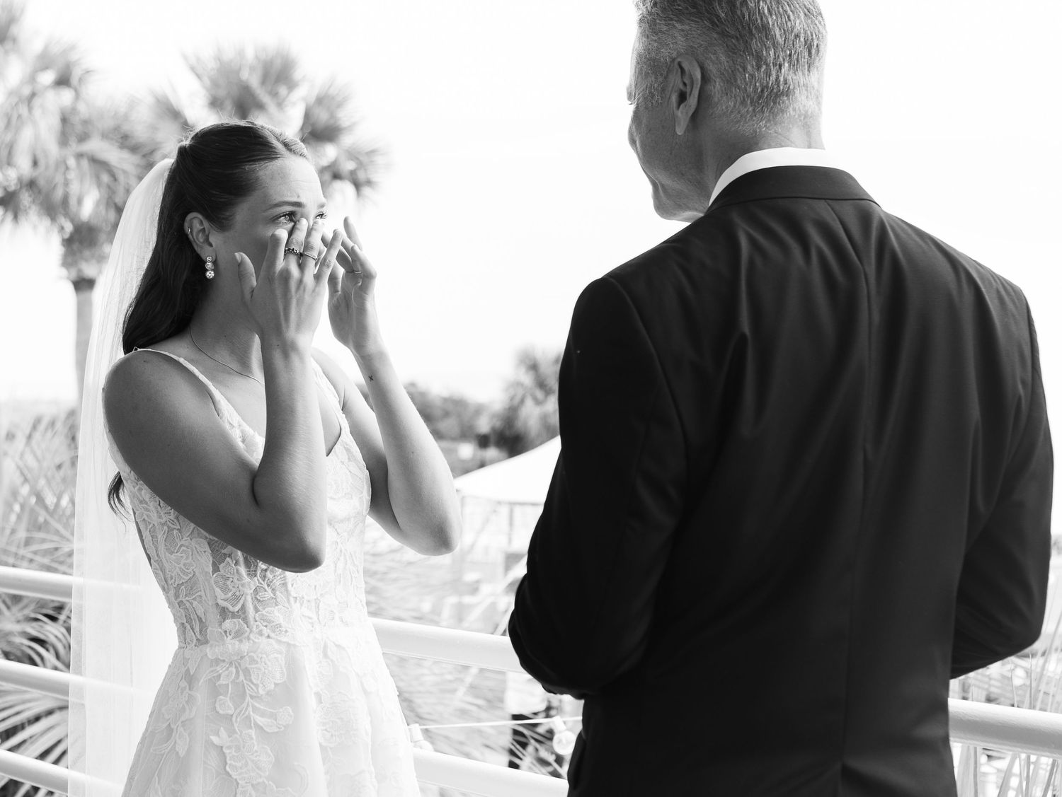Black and white photo of an emotional bride wiping tears during a first look moment at an outdoor wedding ceremony.