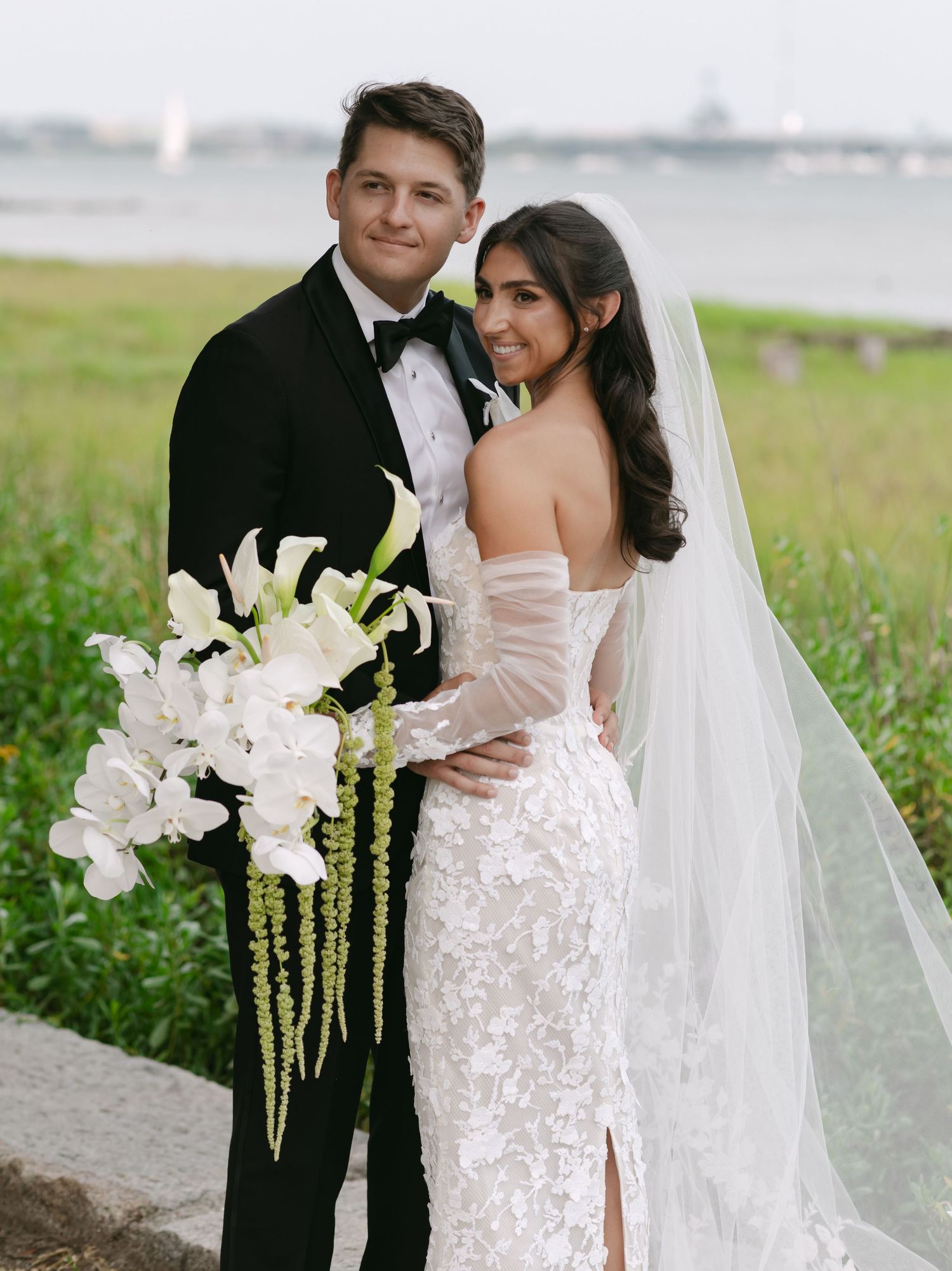 Romantic wedding portraits captured in natural coastal setting with white orchid bouquet.