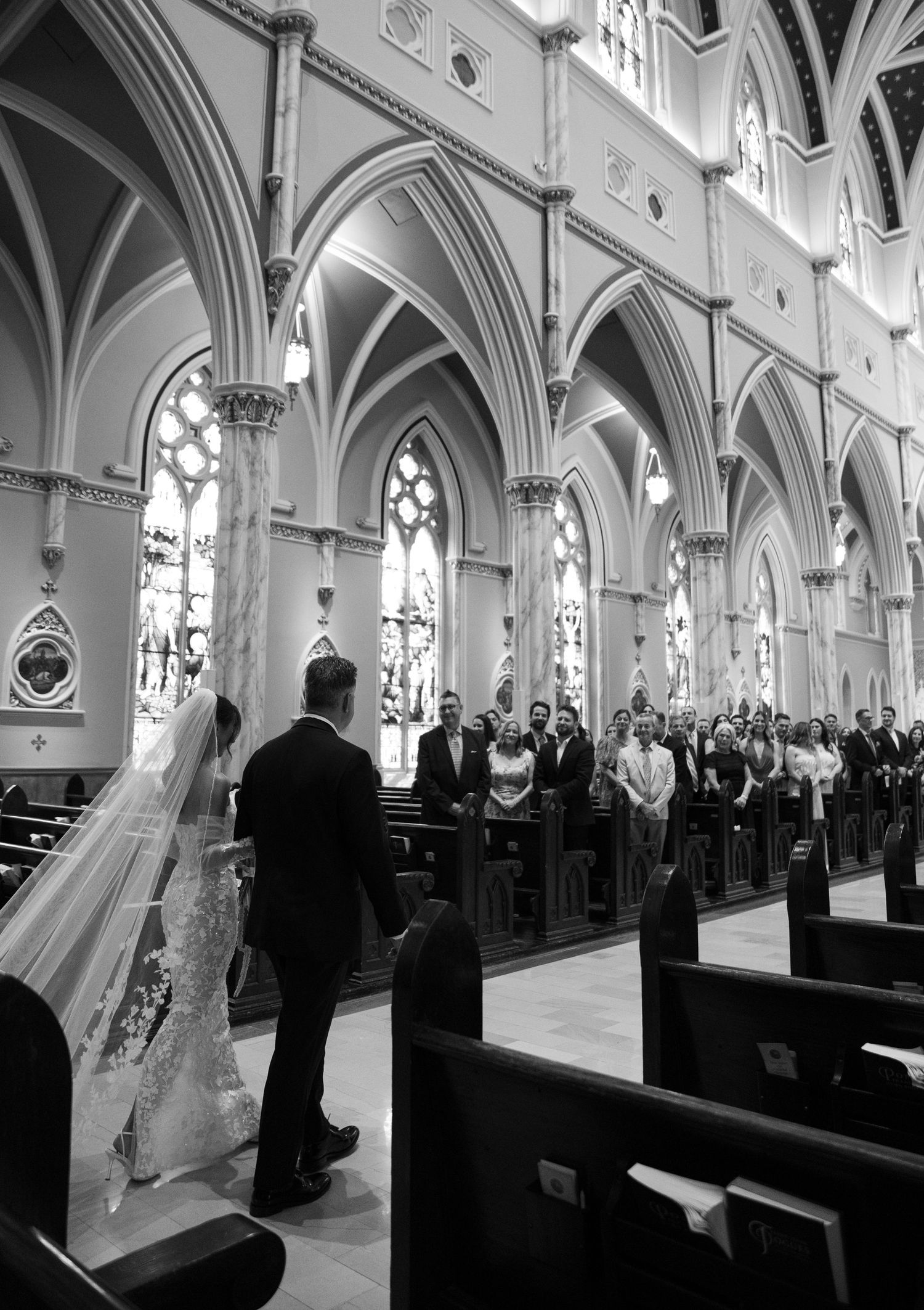 Black and white photograph of wedding ceremony in a cathedral with vaulted gothic architecture.