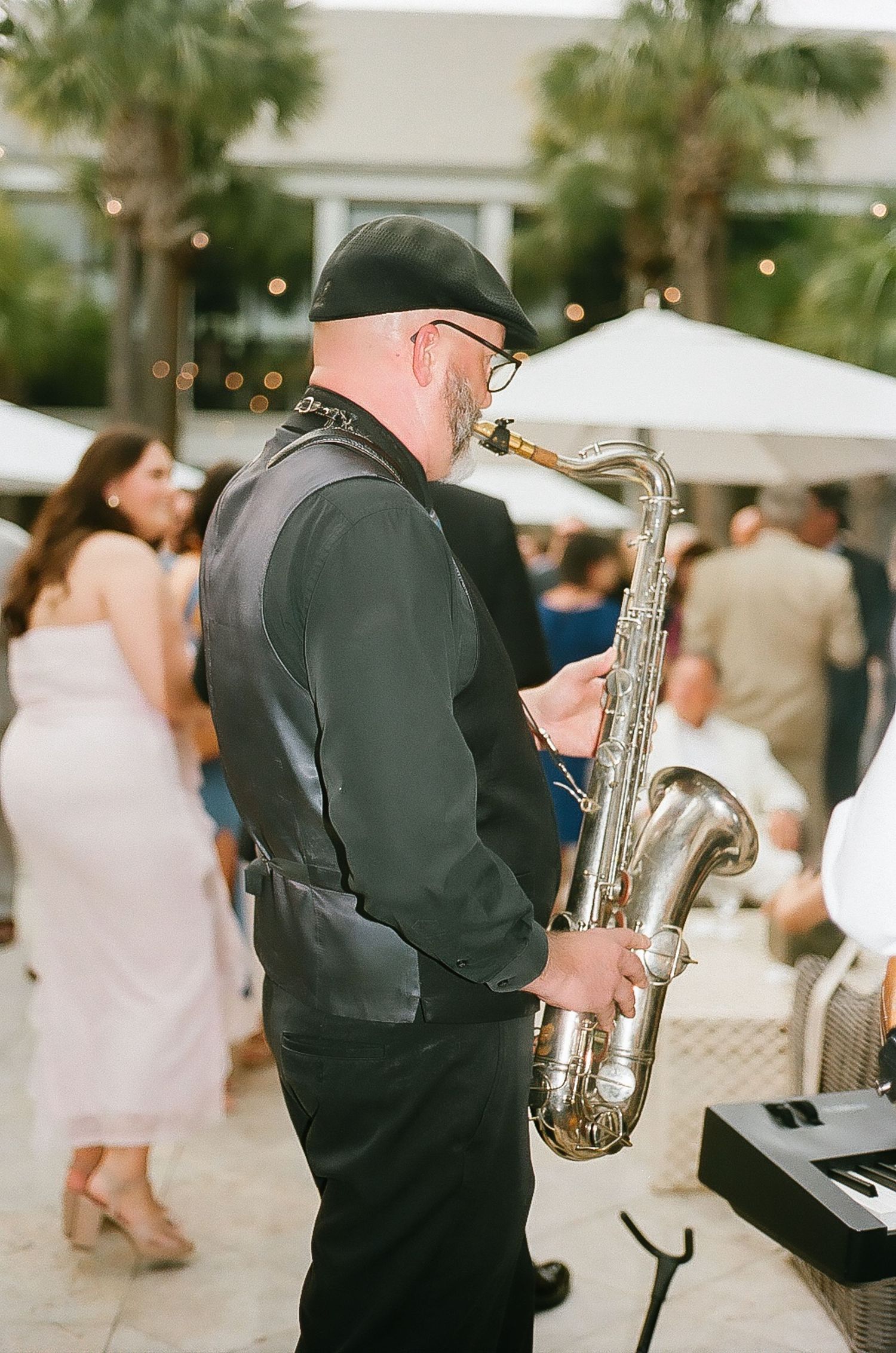 Musicians perform saxophone music at an elegant wedding reception under string lights.