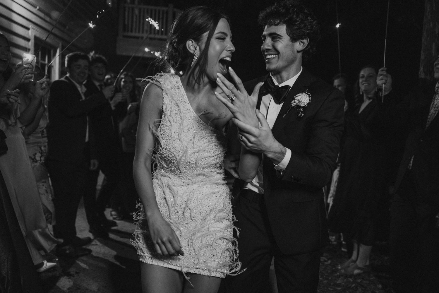 A couple shares their first dance at a wedding reception surrounded by guests holding sparklers.