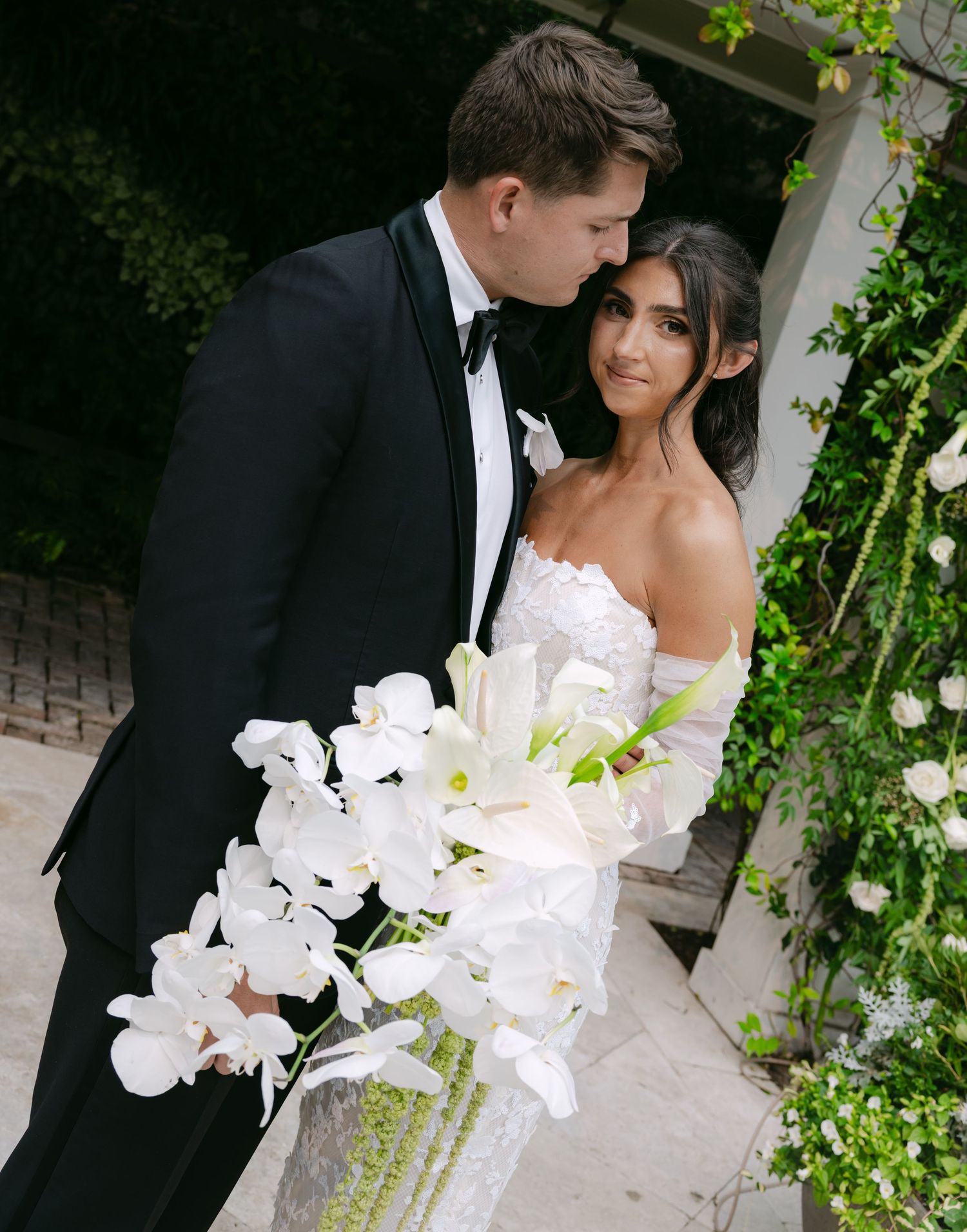 Lush garden wedding setting with white orchids and climbing greenery creates romantic ambiance.