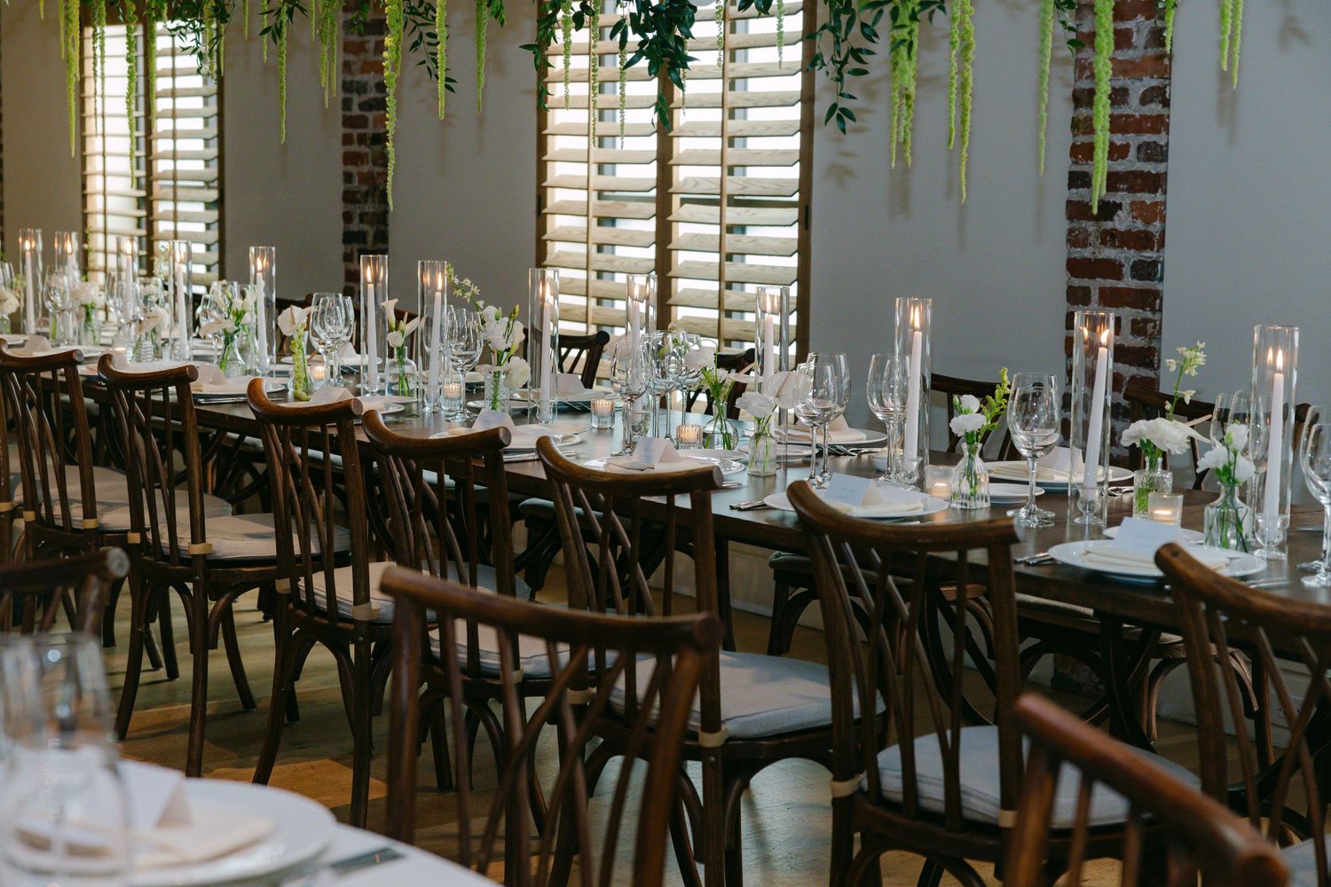 Modern restaurant interior with cross-back chairs and well-set dining tables.