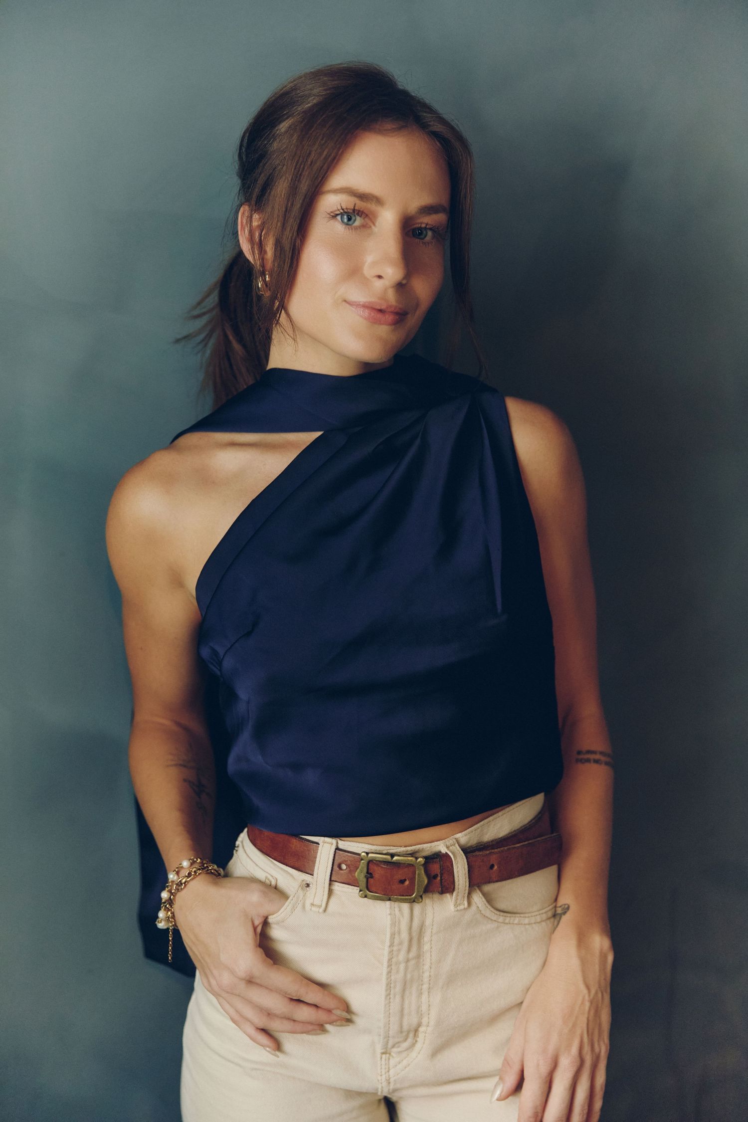 Fashion photo series showing navy sleeveless top paired with beige pants and brown leather belt against moody backdrop.