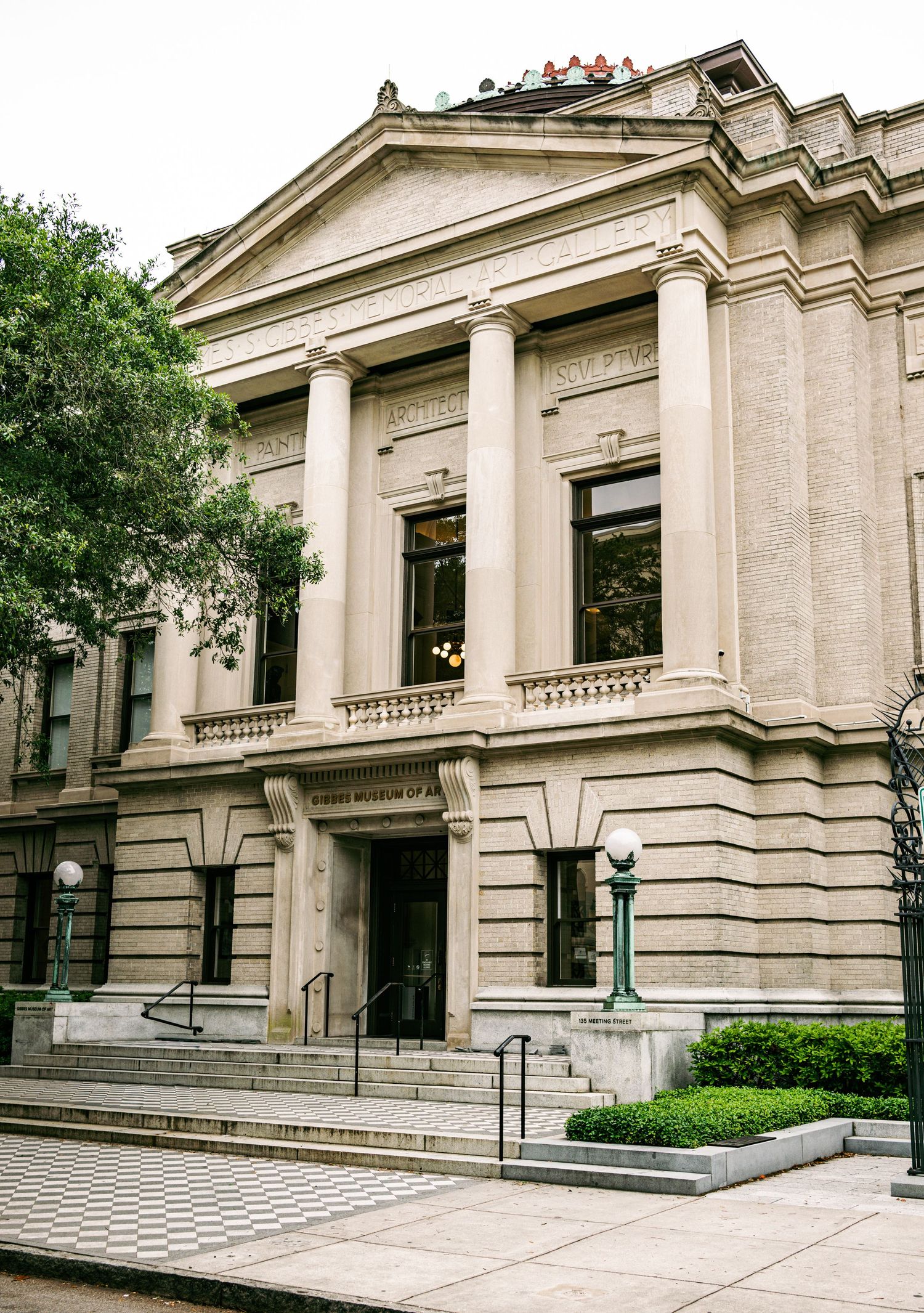 Neoclassical museum building with grand columns and stone facade surrounded by trees.
