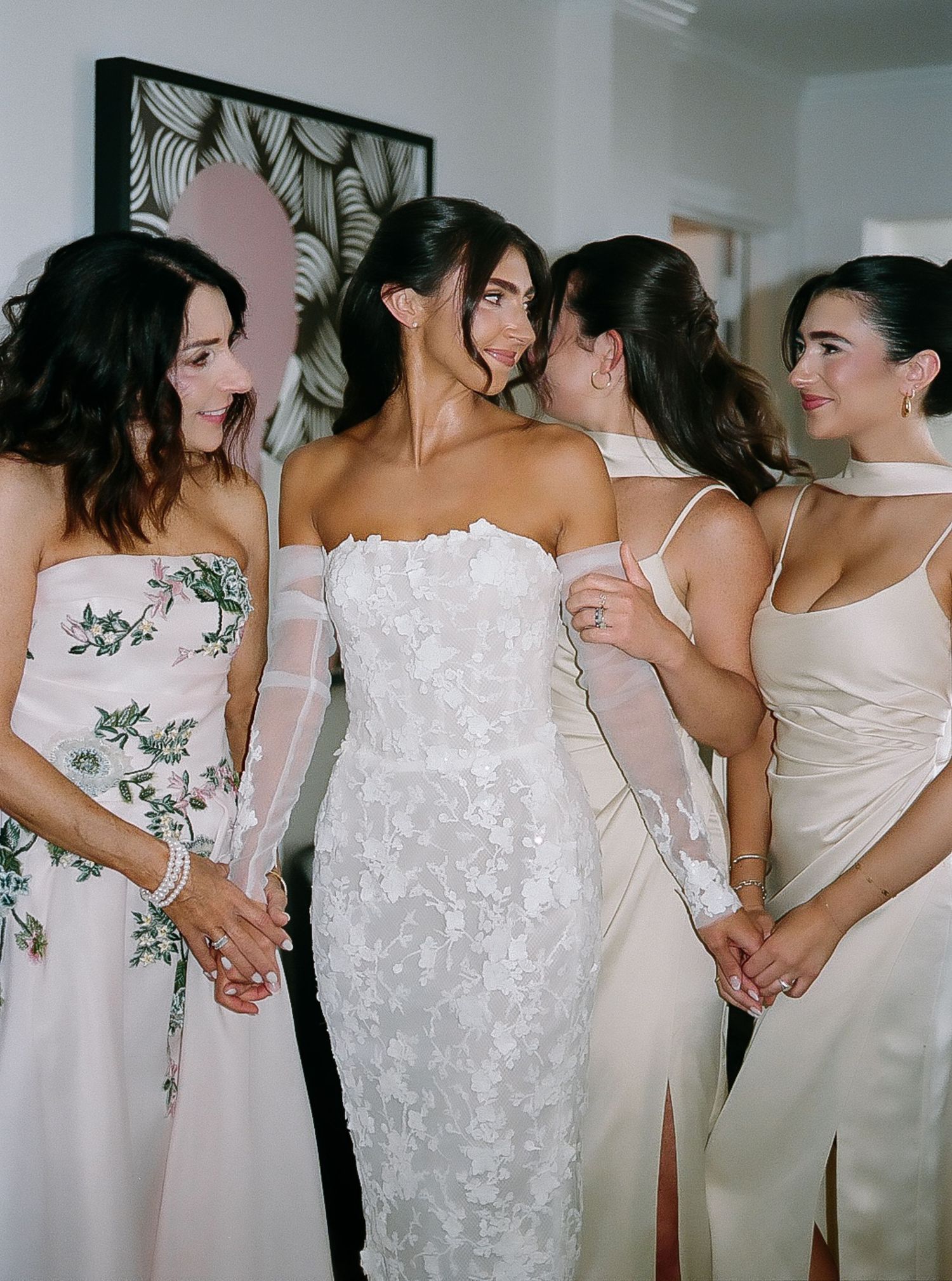 Bridesmaids in elegant white dresses pose together before a wedding ceremony.