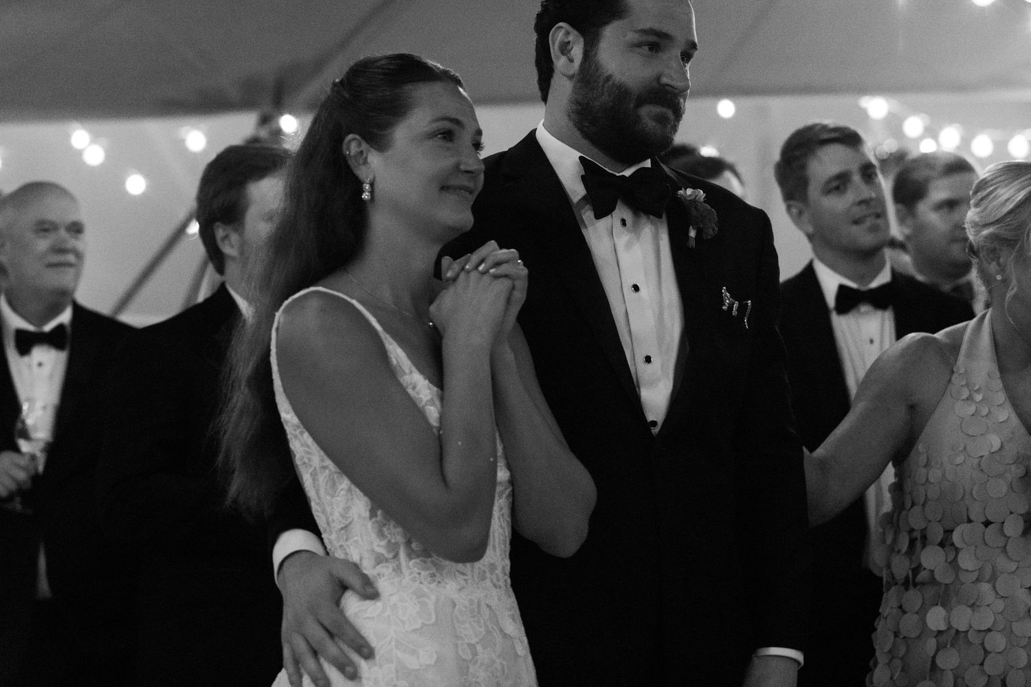 Black and white photo of a smiling bride and groom in formal attire celebrating at their elegant wedding reception.