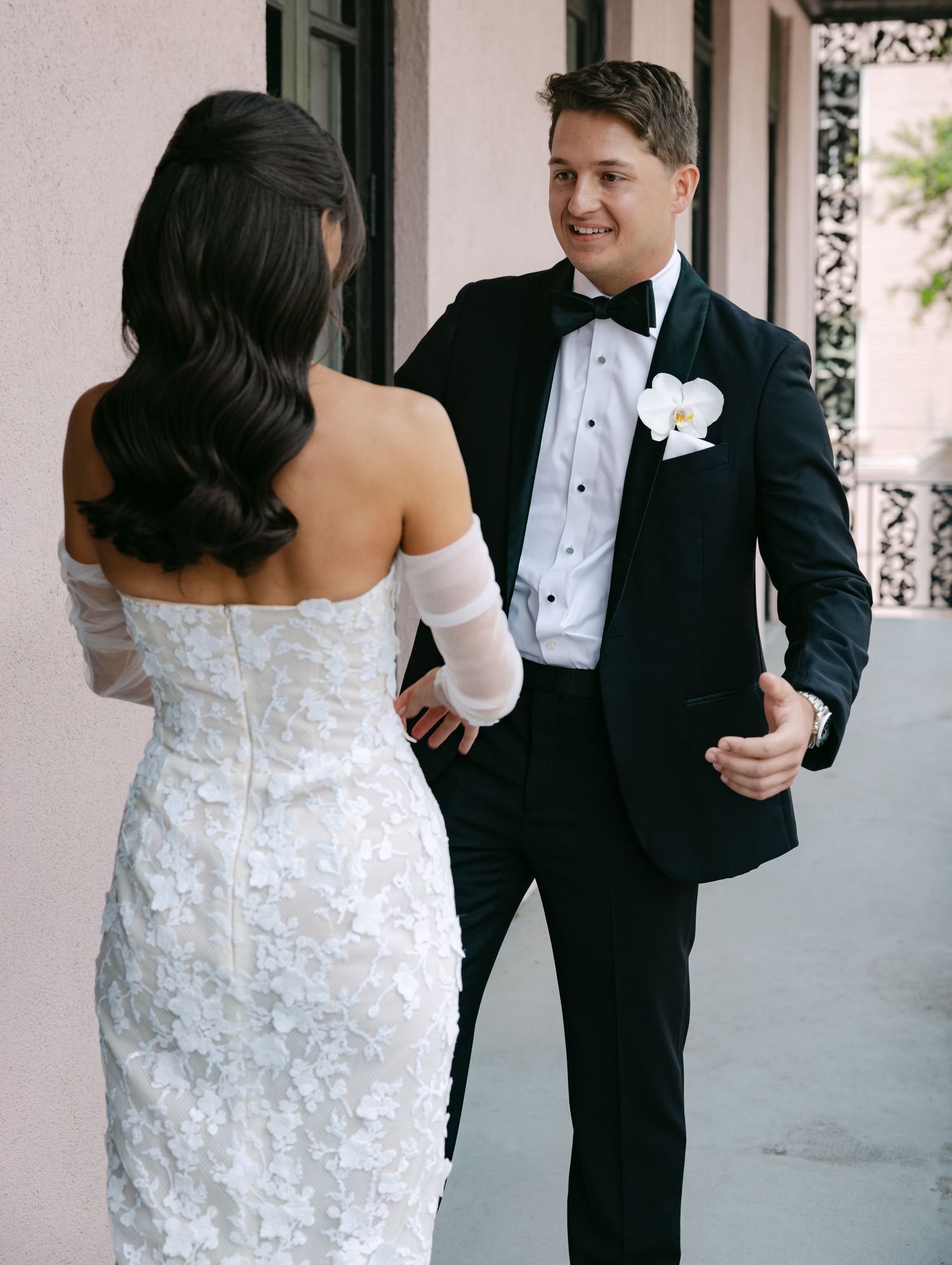 A first look moment between newlyweds on a covered balcony with ornate railings.