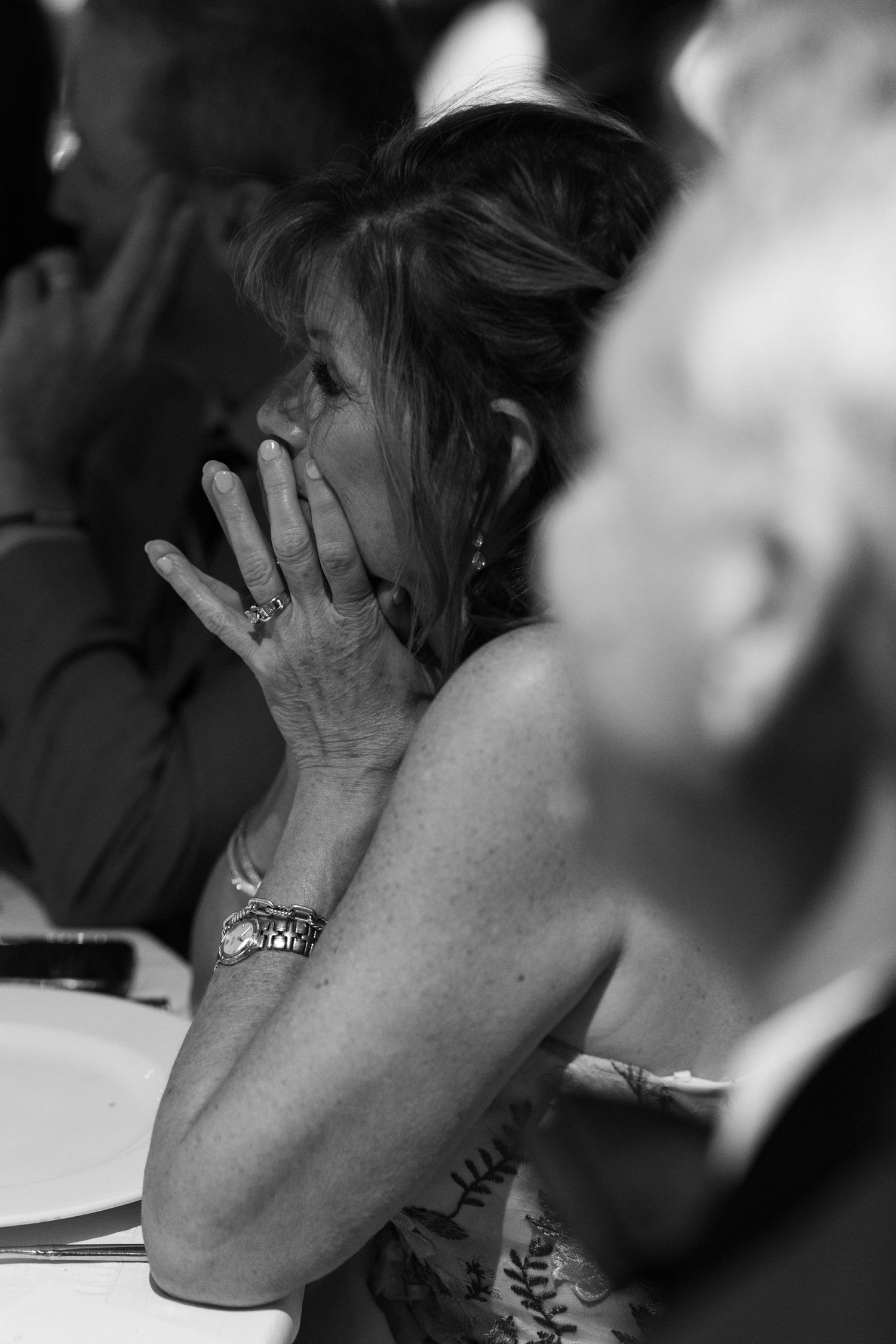 Close-up black and white shot showing wedding guest reactions during emotional moment.