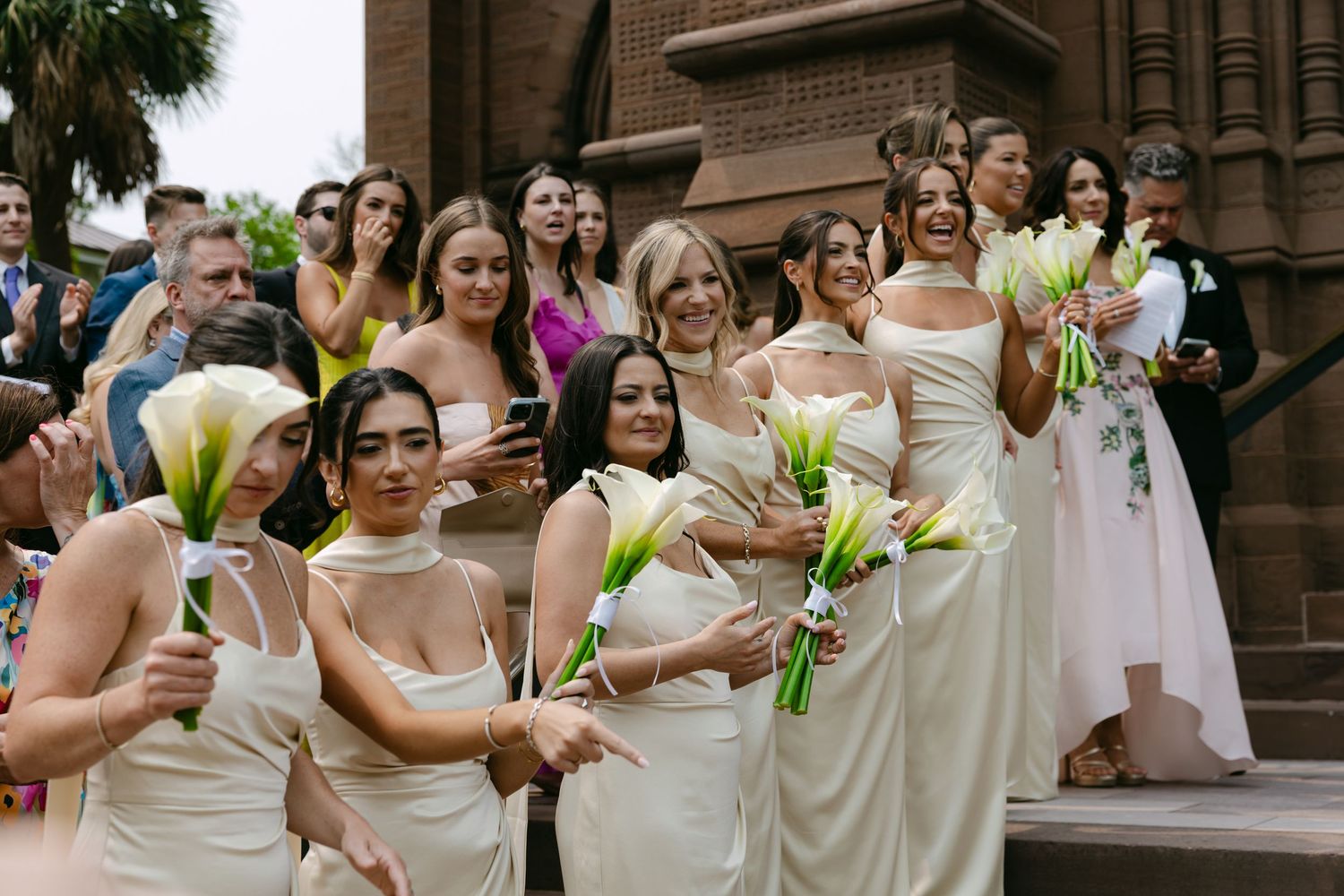 Wedding guests and bridal party mingle outside Gothic church entrance.