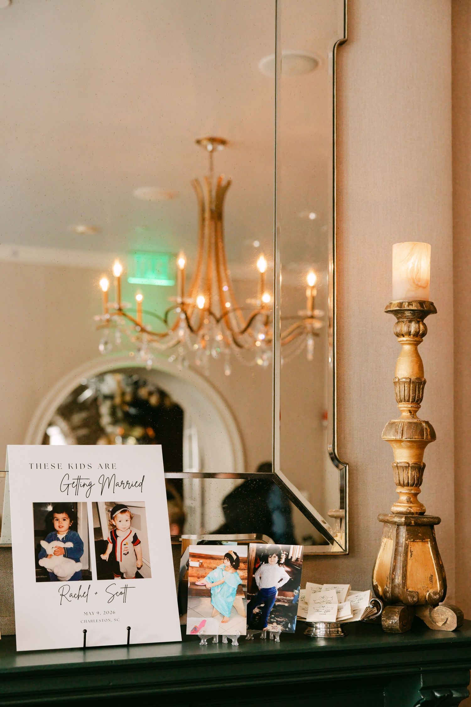 Wedding sign reads These Kids Are Getting Married with childhood photos on elegant mantel.