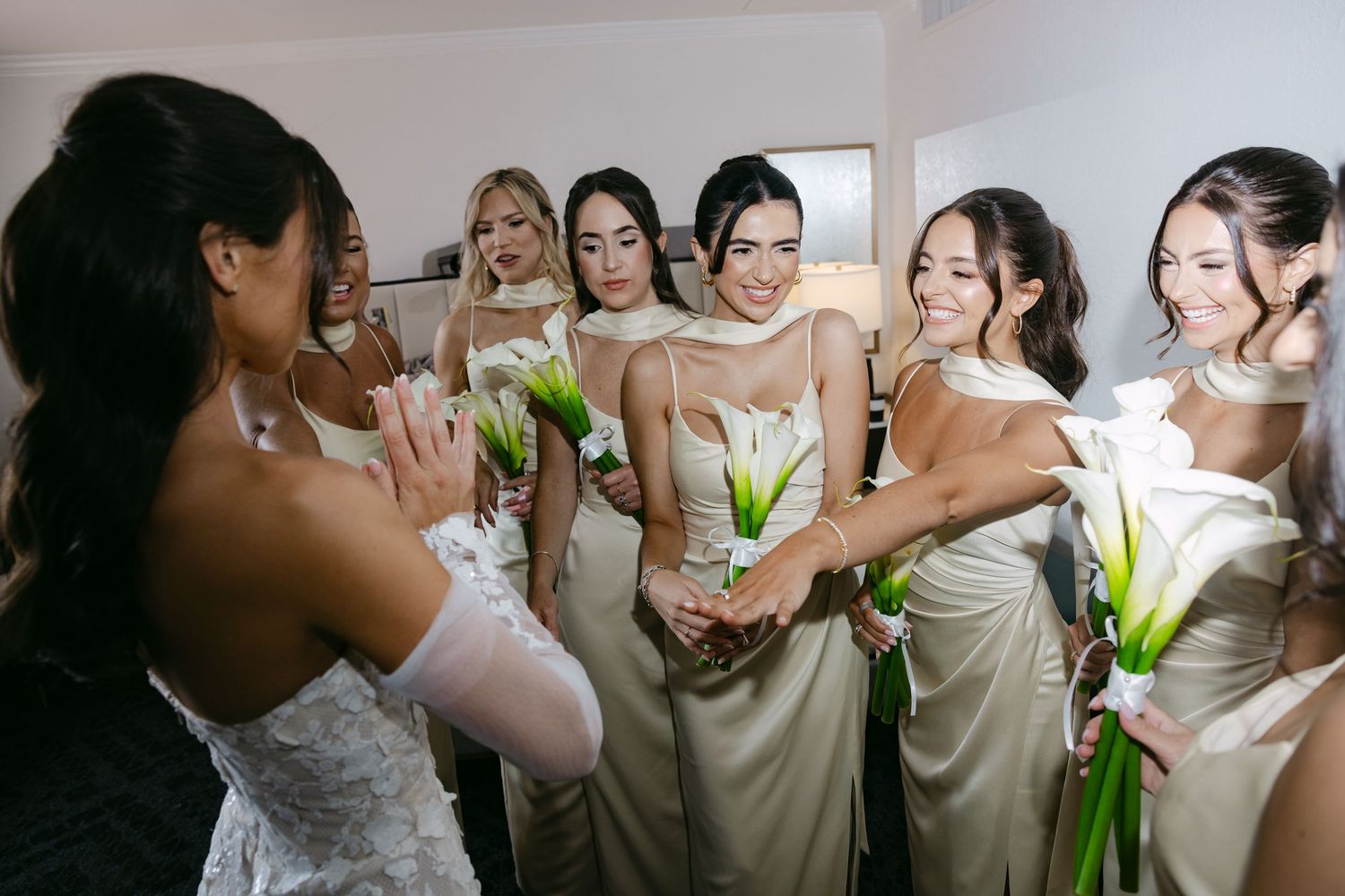 Wedding party members in ivory dresses gathered for candid pre-ceremony moments.