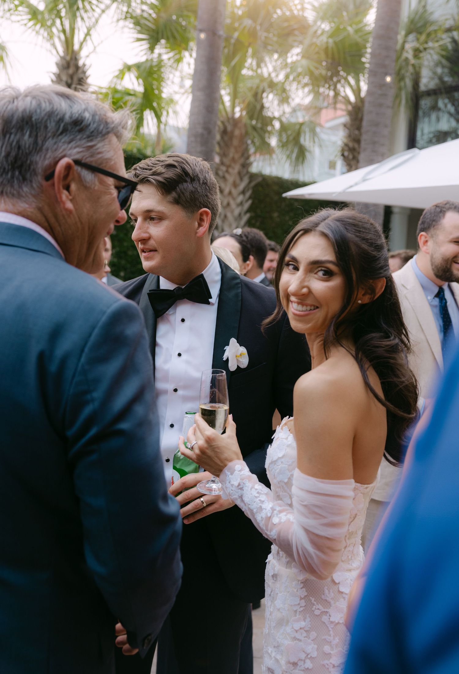 Wedding celebration candid moments captured during an outdoor reception with palm trees.