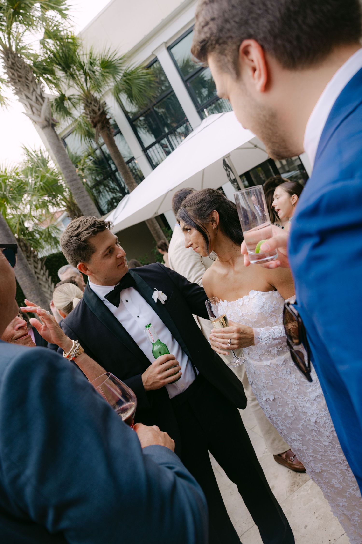 Wedding guests in formal attire mingle and socialize during an outdoor cocktail reception.