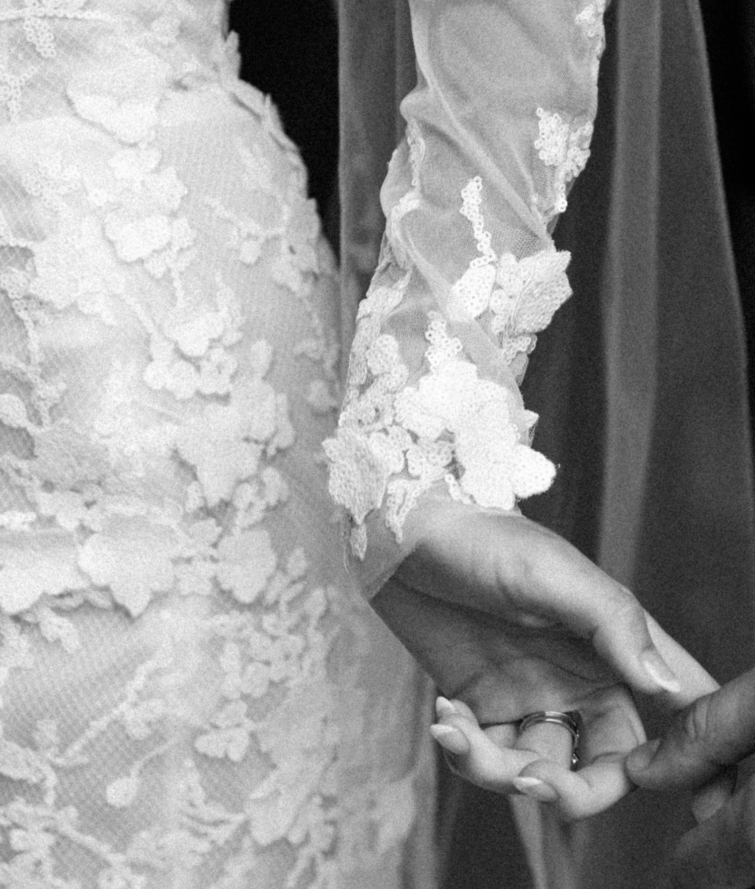 Close-up details of delicate white floral appliques on wedding dress.