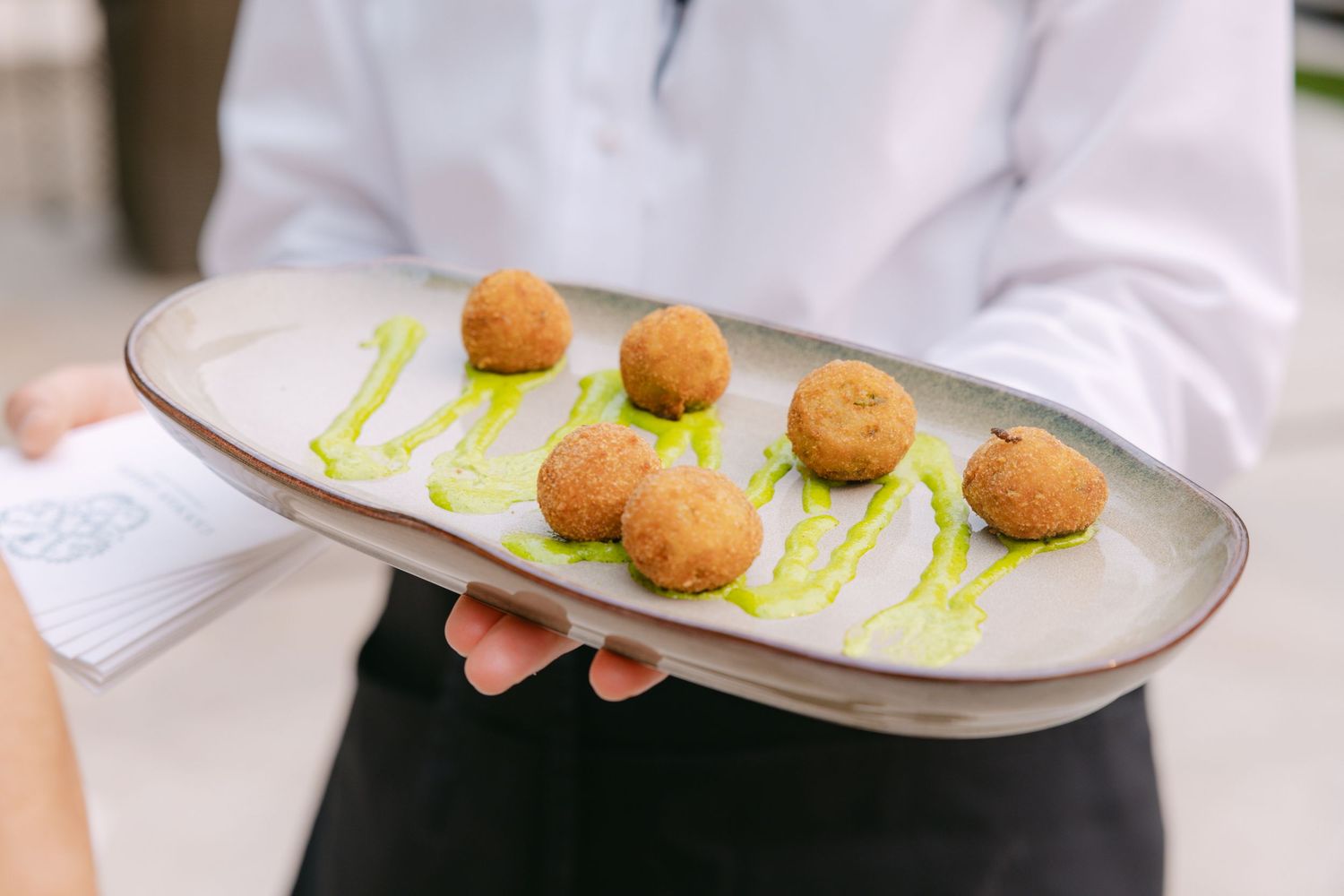 Wedding appetizers being served on elegant white plates by catering staff.
