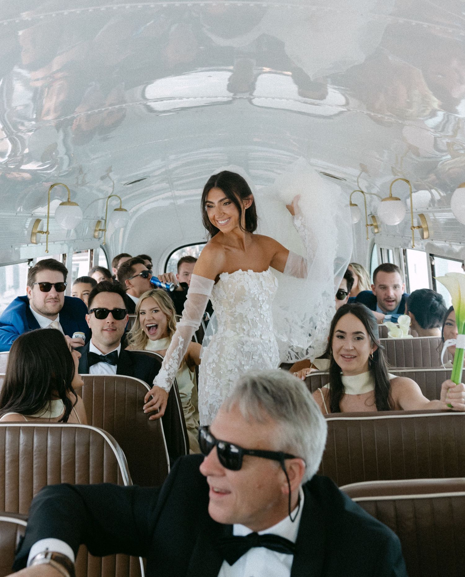 Wedding party riding in a vintage bus with elegant decorations and floral arrangements.