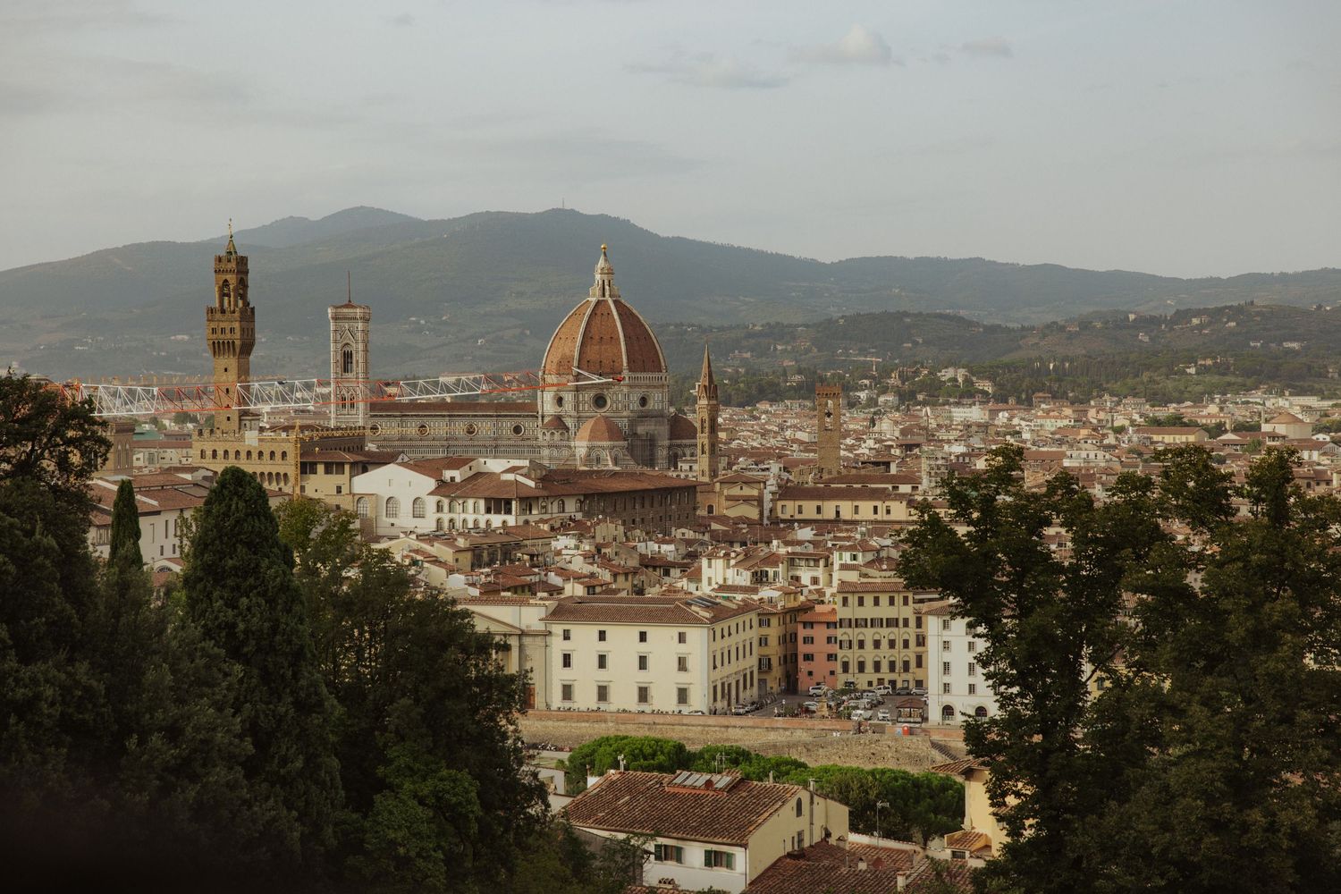Panoramic cityscape view of Florence, Italy showing historic architecture and the Duomo cathedral against rolling hills.