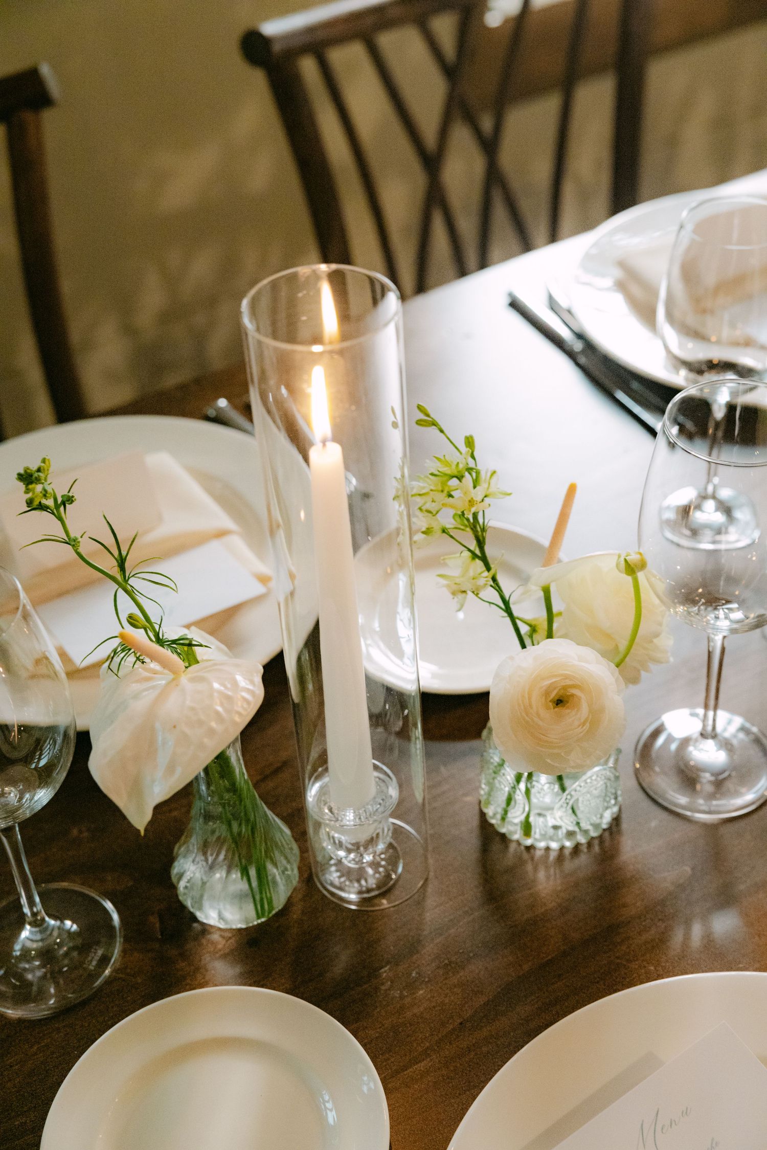 Close-up of wedding table decor featuring delicate white flowers in small glass vases.