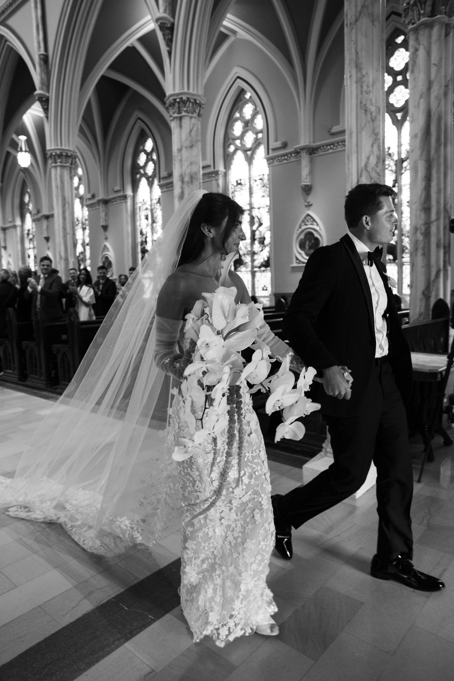 A couple poses in sequences at a cathedral wedding with elegant architecture and stained glass windows in the background.