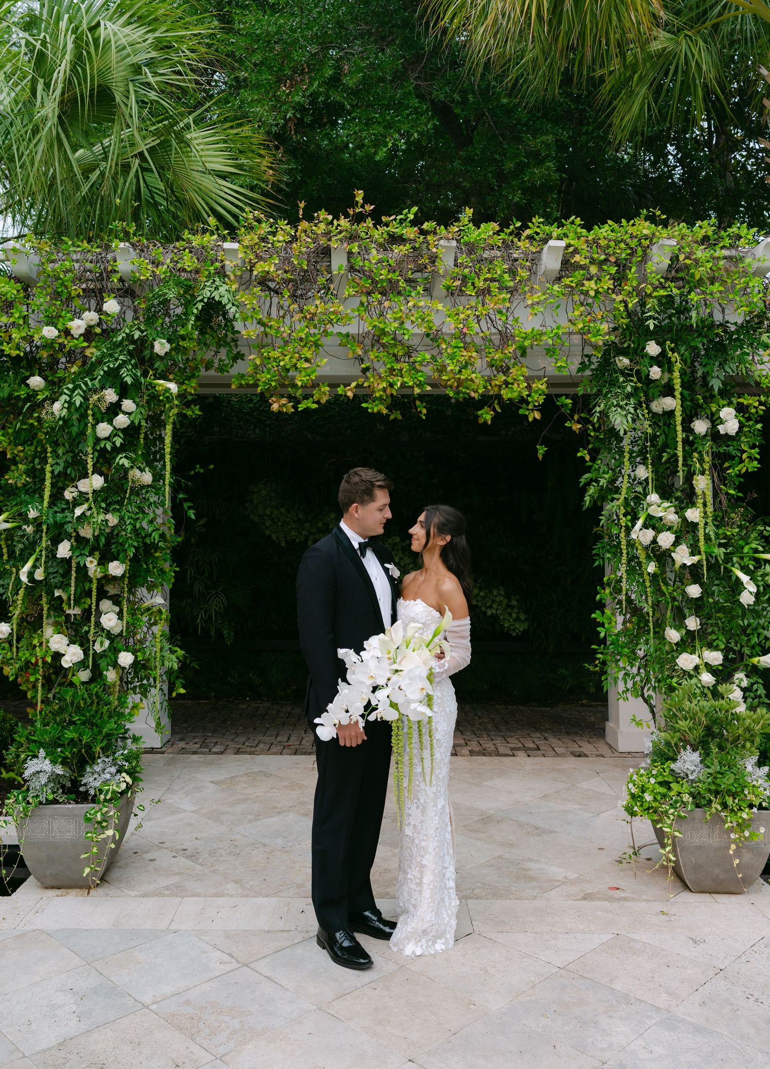 Tropical garden wedding venue features climbing roses and elegant stone pathway.