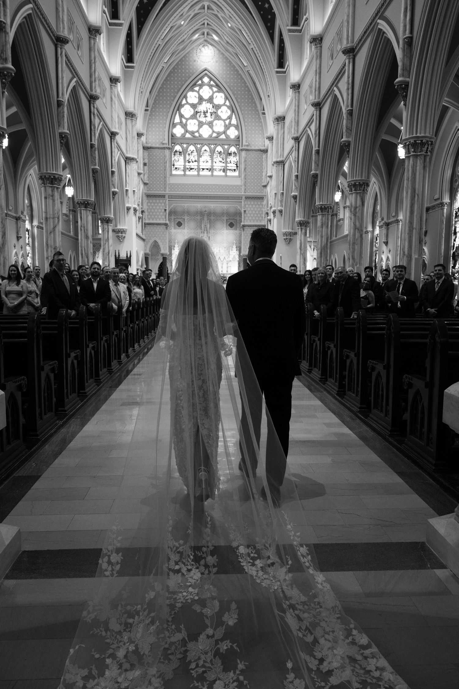 Dramatic black and white photo of cathedral wedding ceremony with long flowing veil.