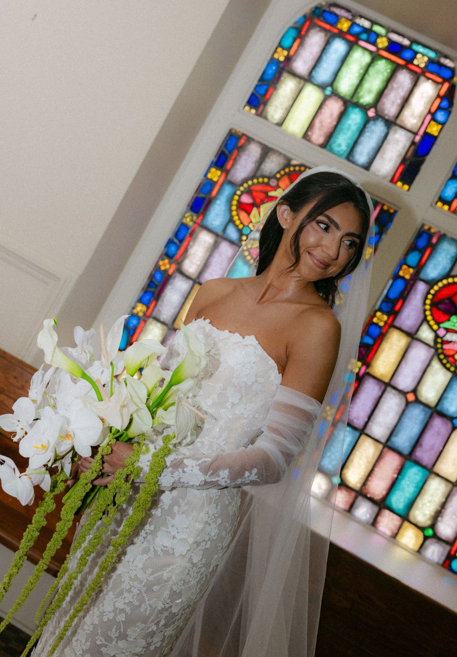 Elegant bridal portrait with white flowers against colorful stained glass windows.