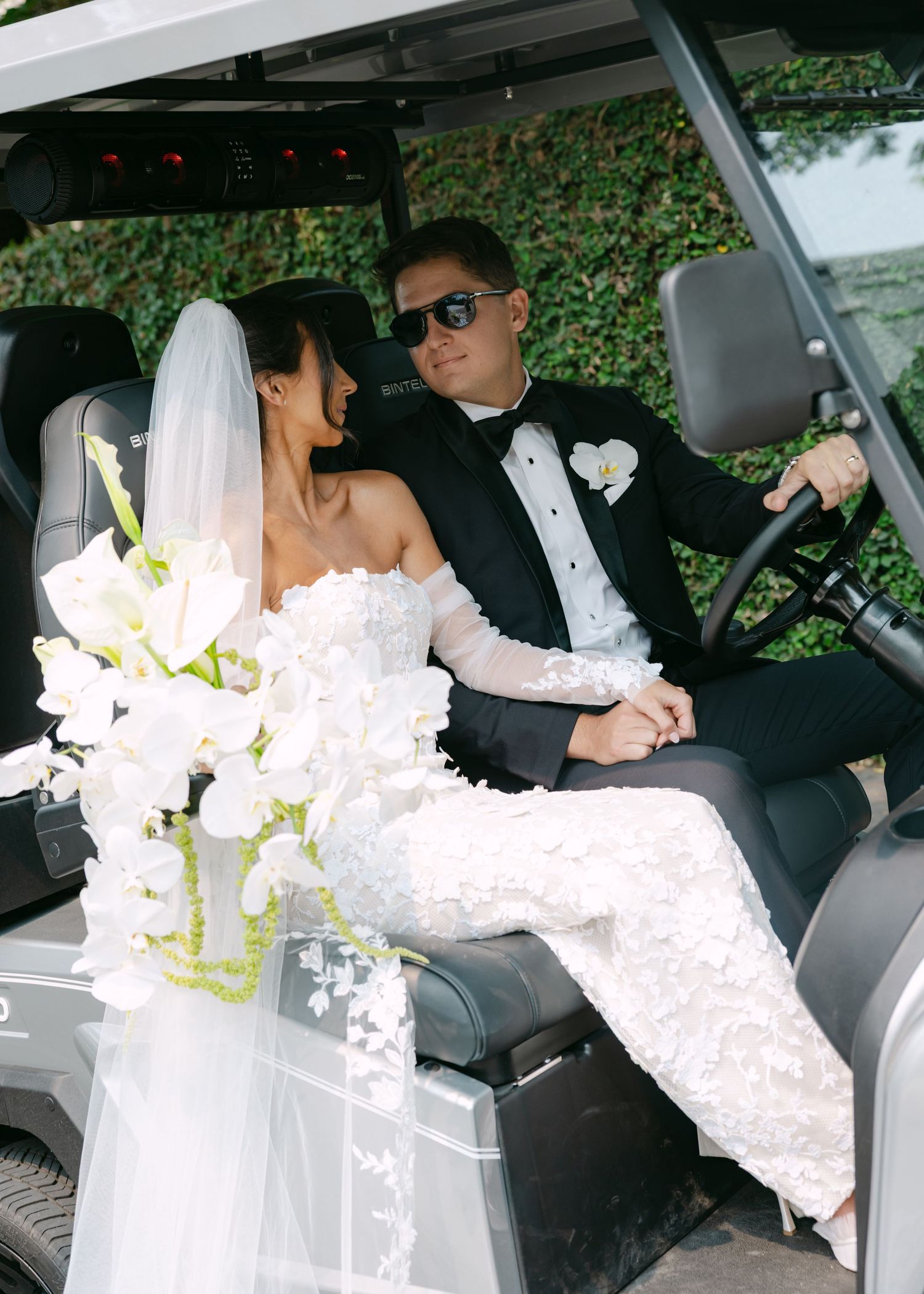 Wedding couple relaxing inside a luxury golf cart with beautiful floral decorations.